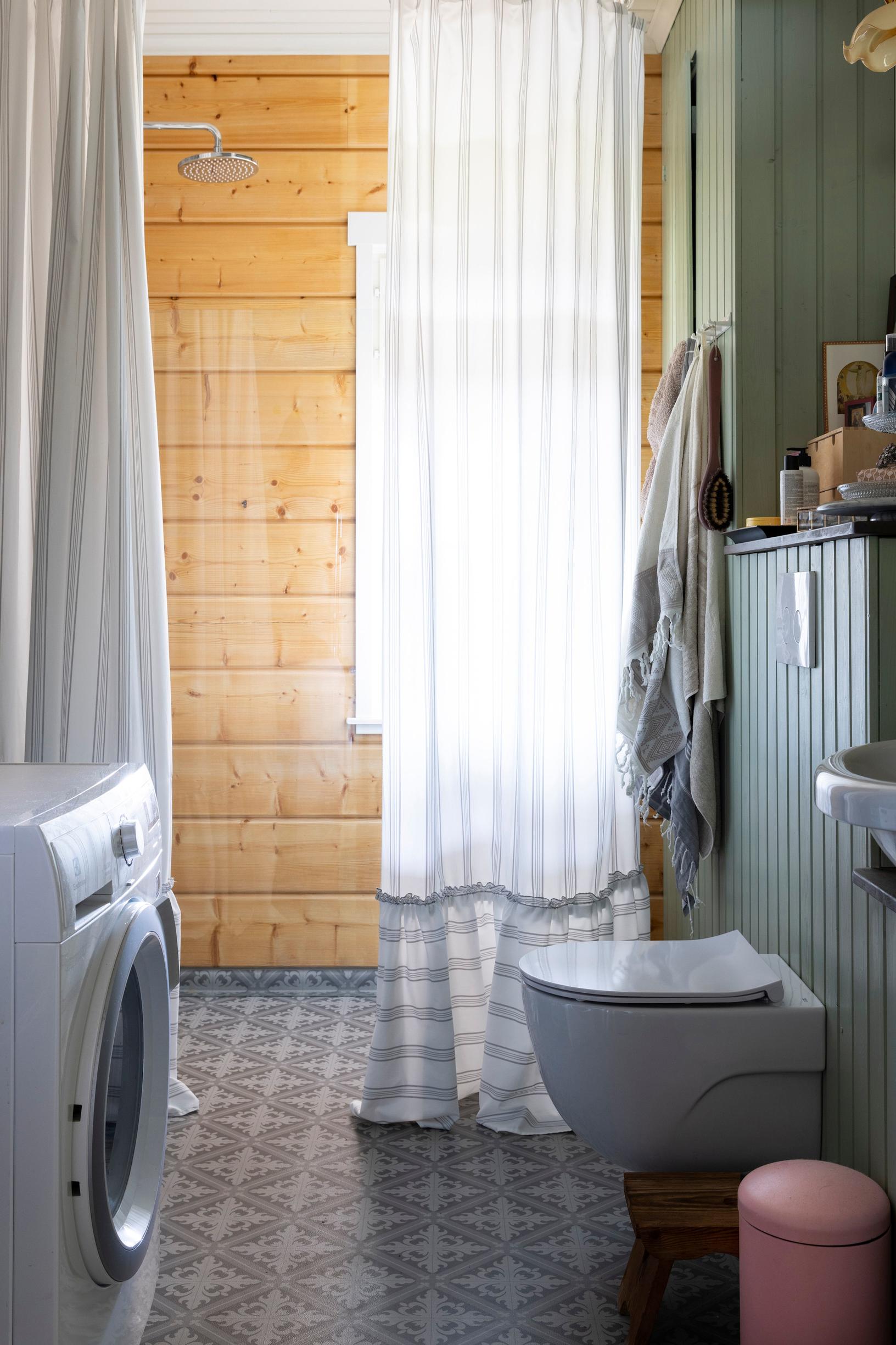 The bathroom features a patterned tile floor and a log wall behind the shower.