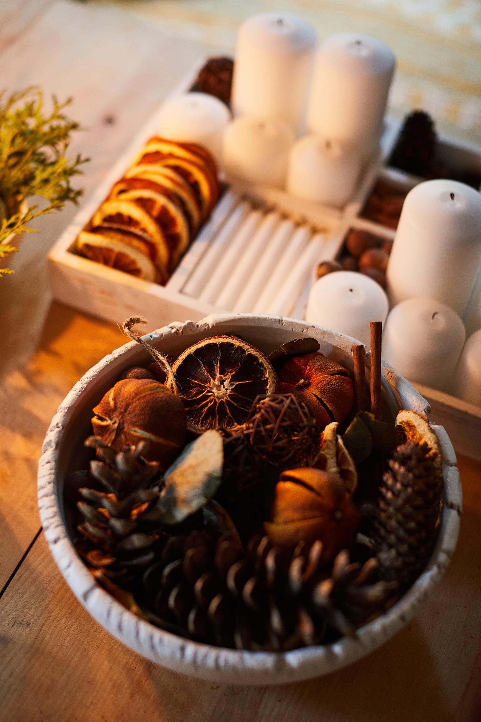 A stash of orange slices, pine cones, star anise, and various candles.