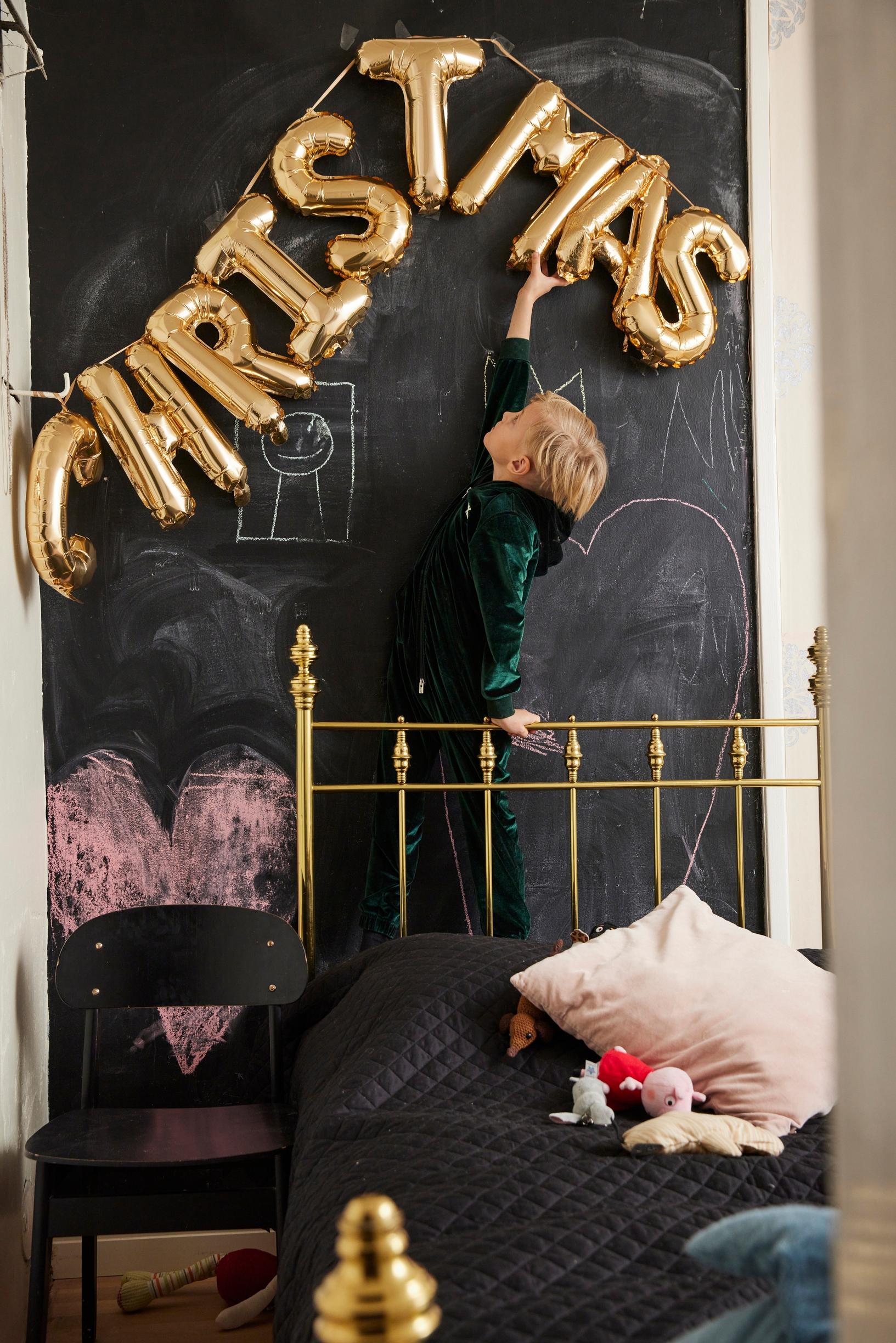 A golden bed in front of a chalkboard wall
