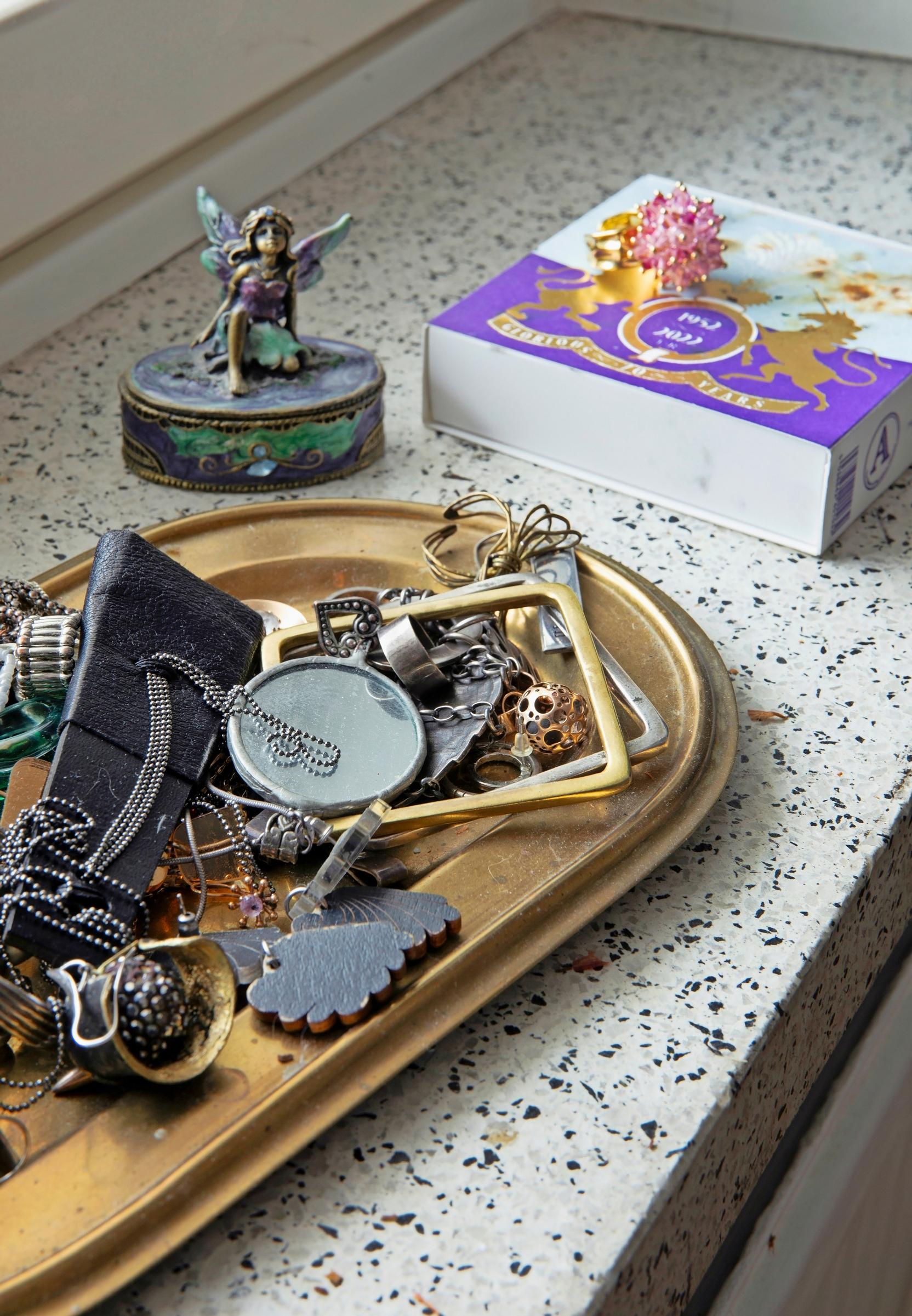 On the windowsill, a dish holding various pieces of jewelry and other items.