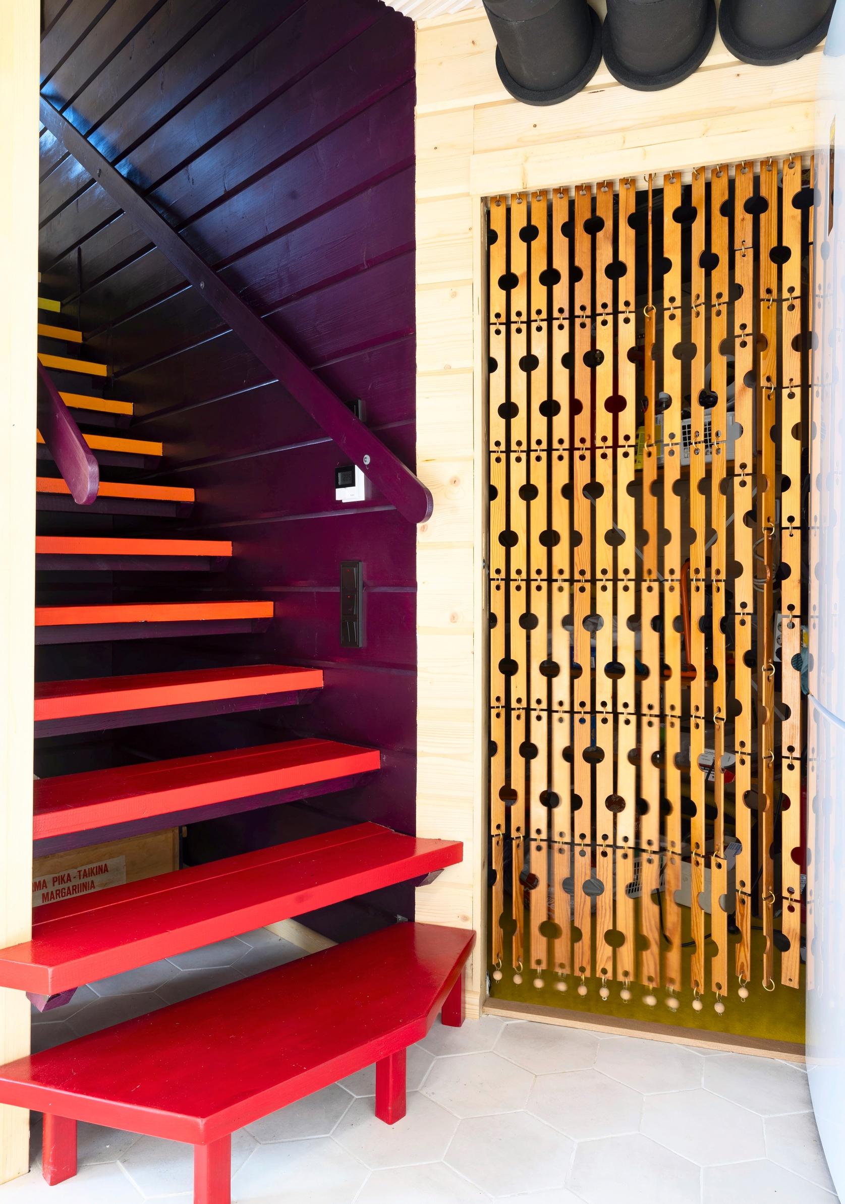 A wooden divider next to the red stairs leading upstairs