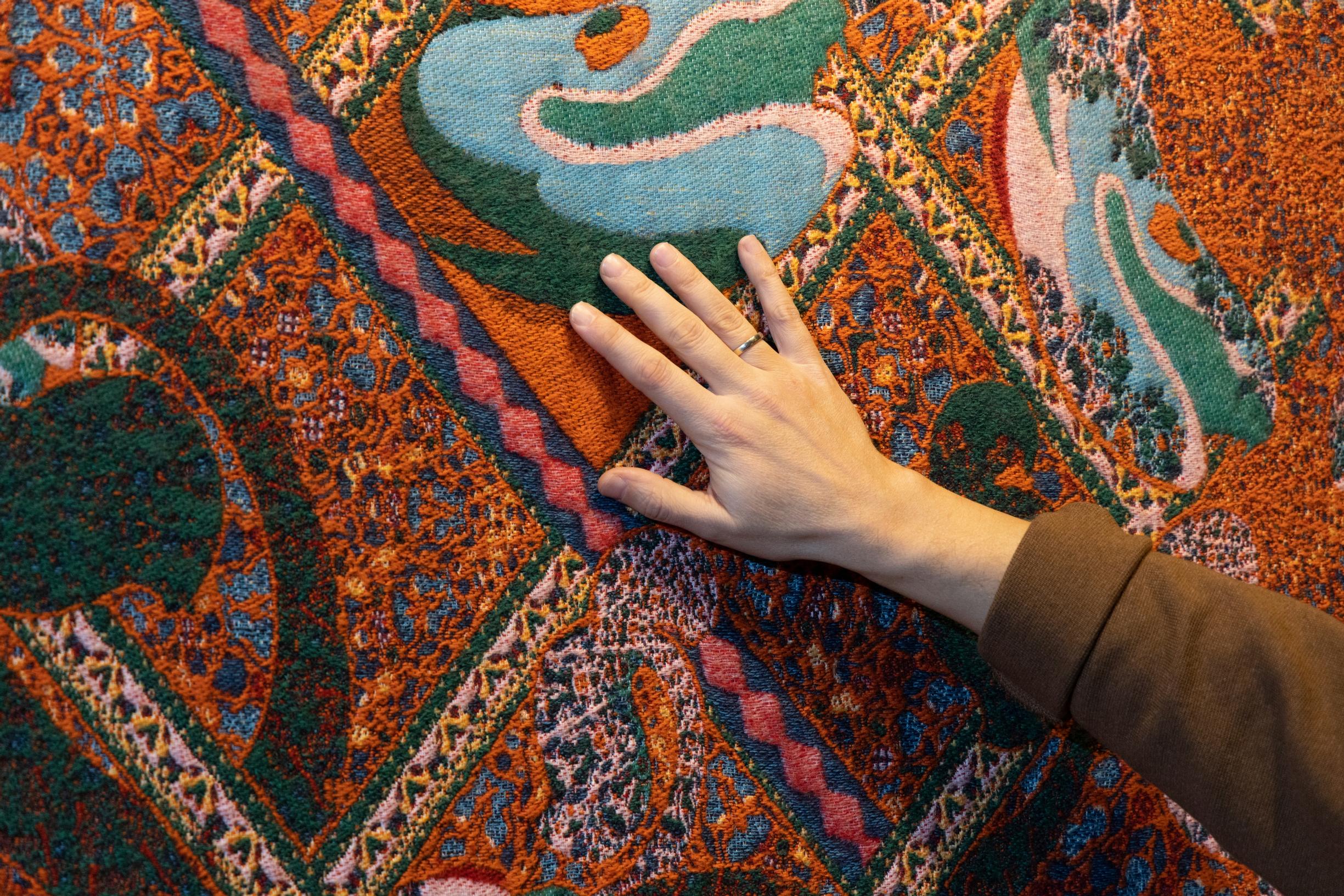 Kustaa Saksi’s hand on the surface of a textile artwork