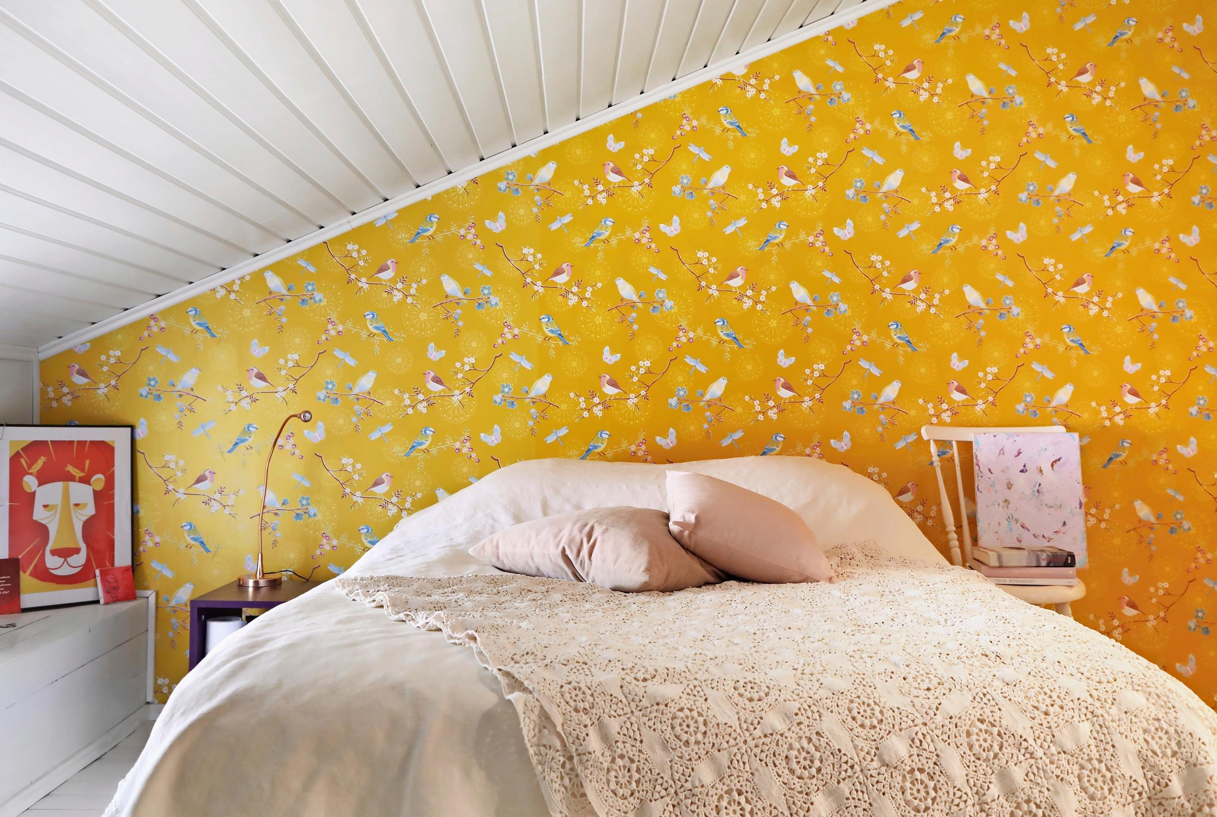 A photo of the bedroom in a wooden home with yellow wallpaper.