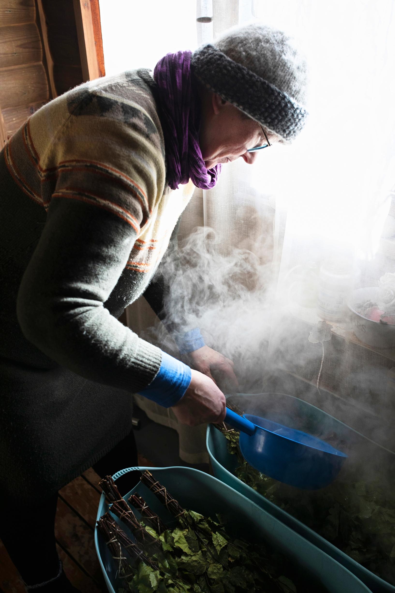 Kirsti pours hot water over the birch whisk