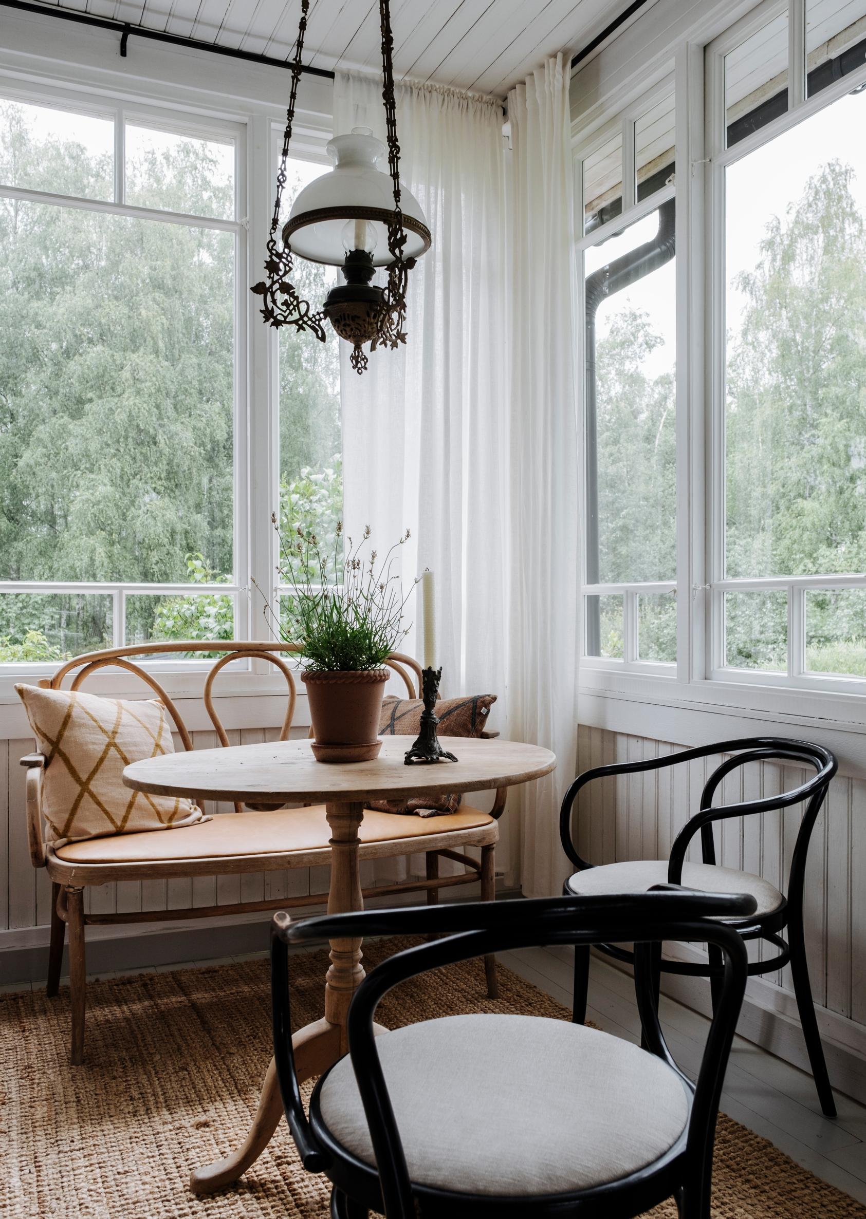 A wooden sofa, table, and two chairs on the porch.