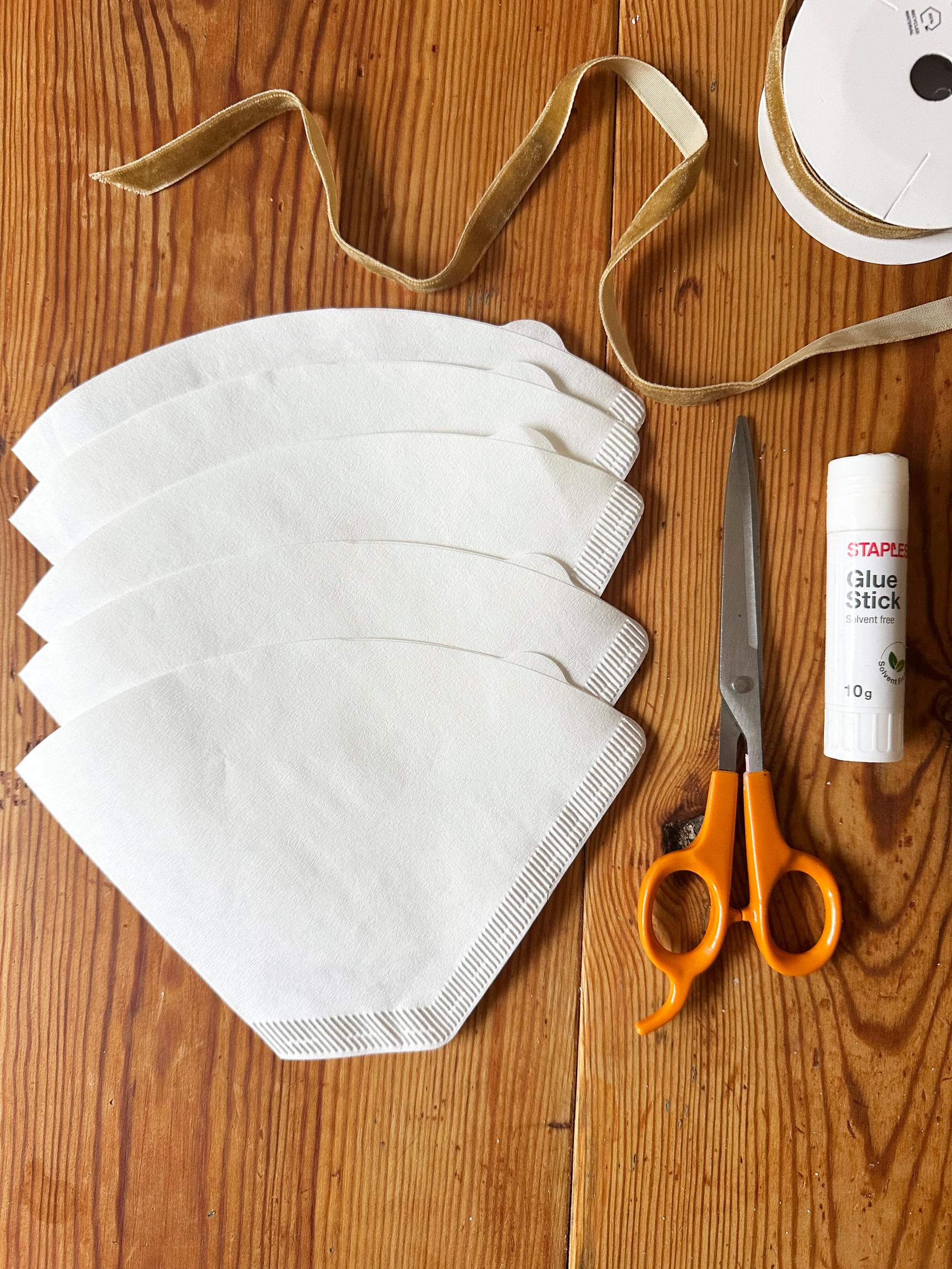 Supplies for coffee filter stars: filters, scissors, glue, and ribbon.