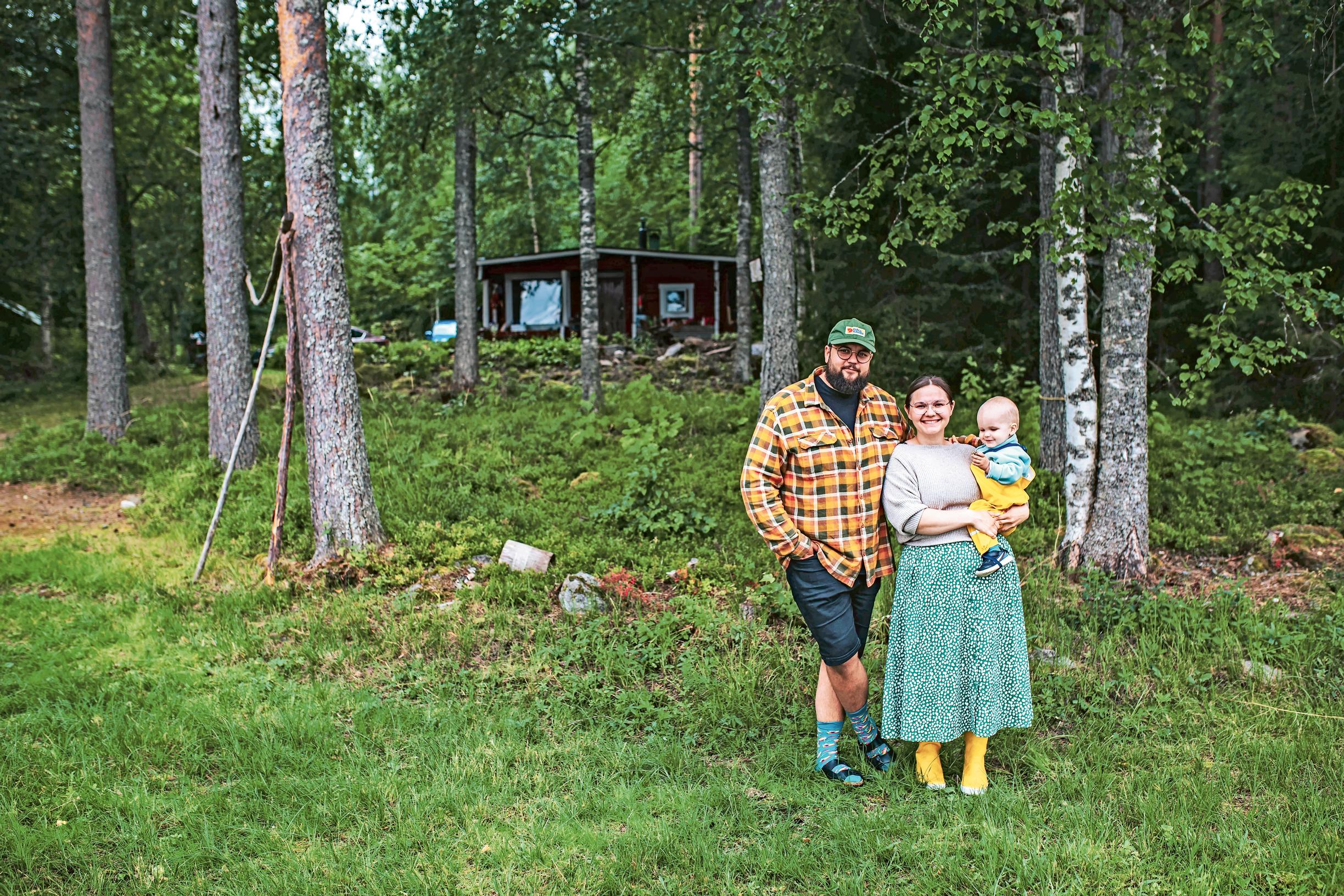 Dad and mom in front of the cottage, mom holding their little boy.