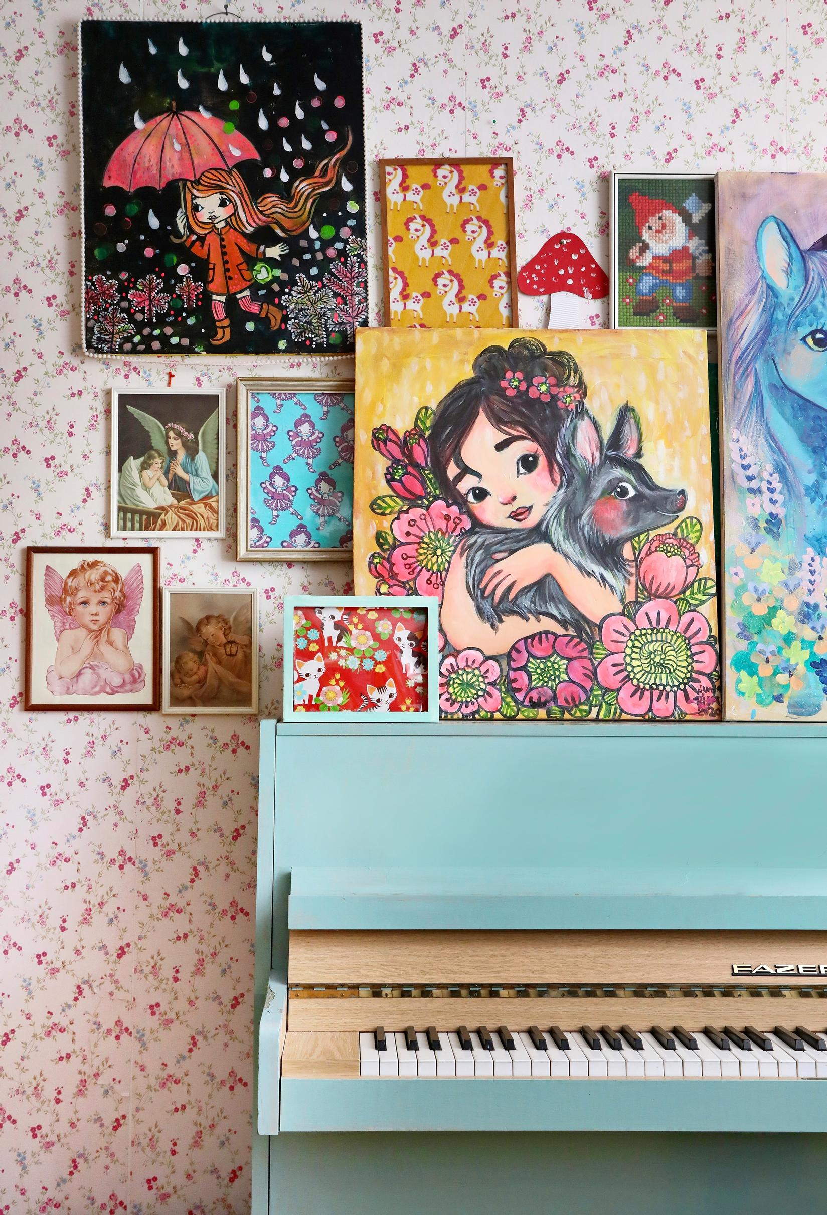 The wall behind the turquoise piano is filled with paintings by Leena Rissa.