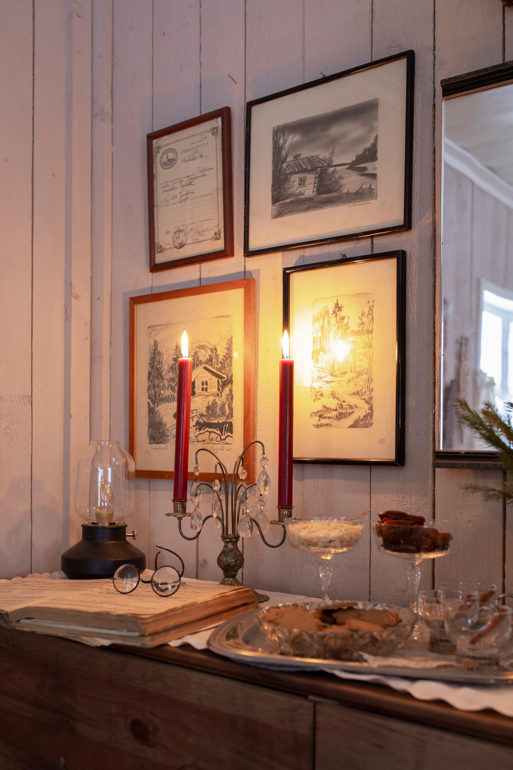 A candelabra, paintings, and Christmas treats on a sideboard.