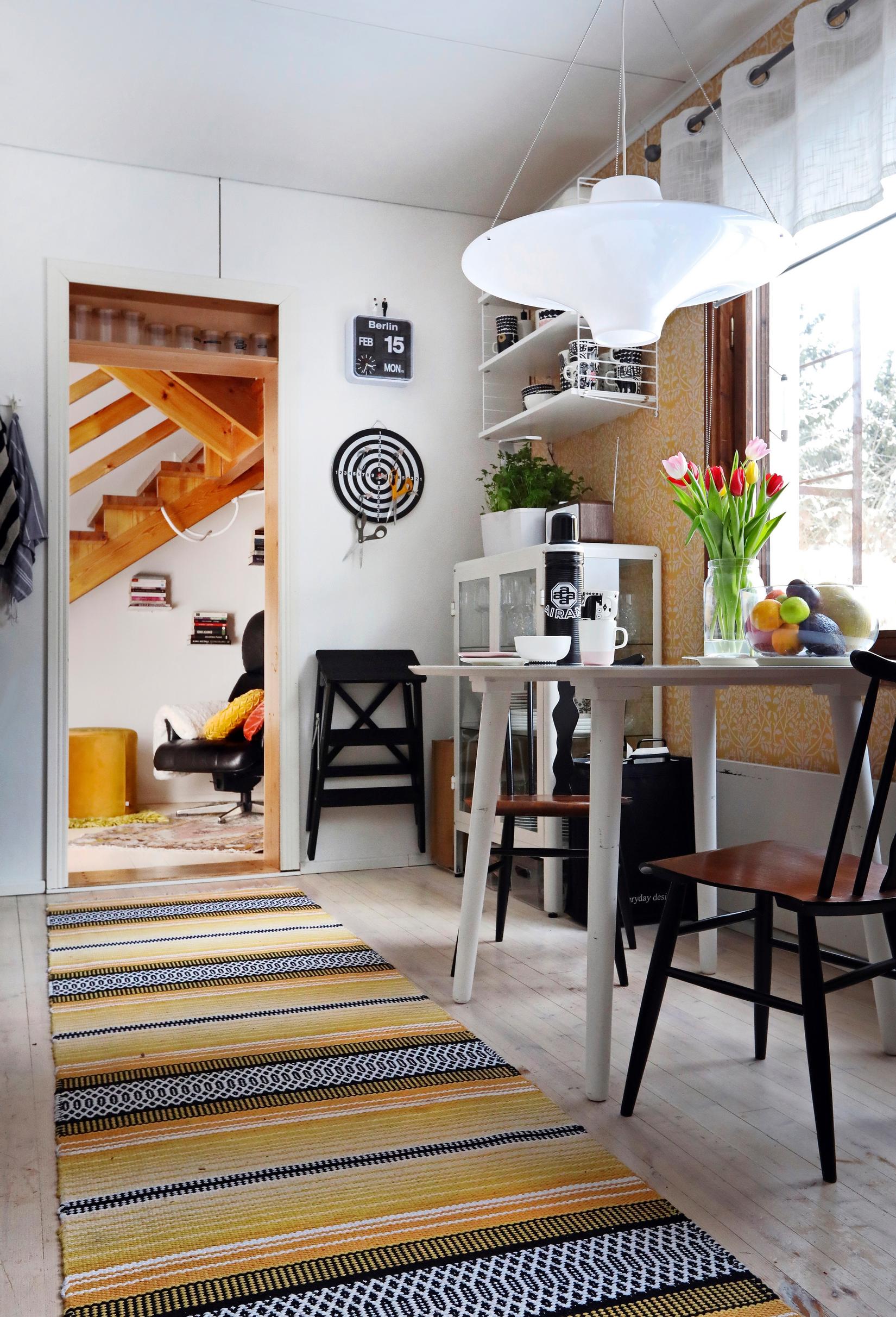 A long yellowish rag rug next to the dining table