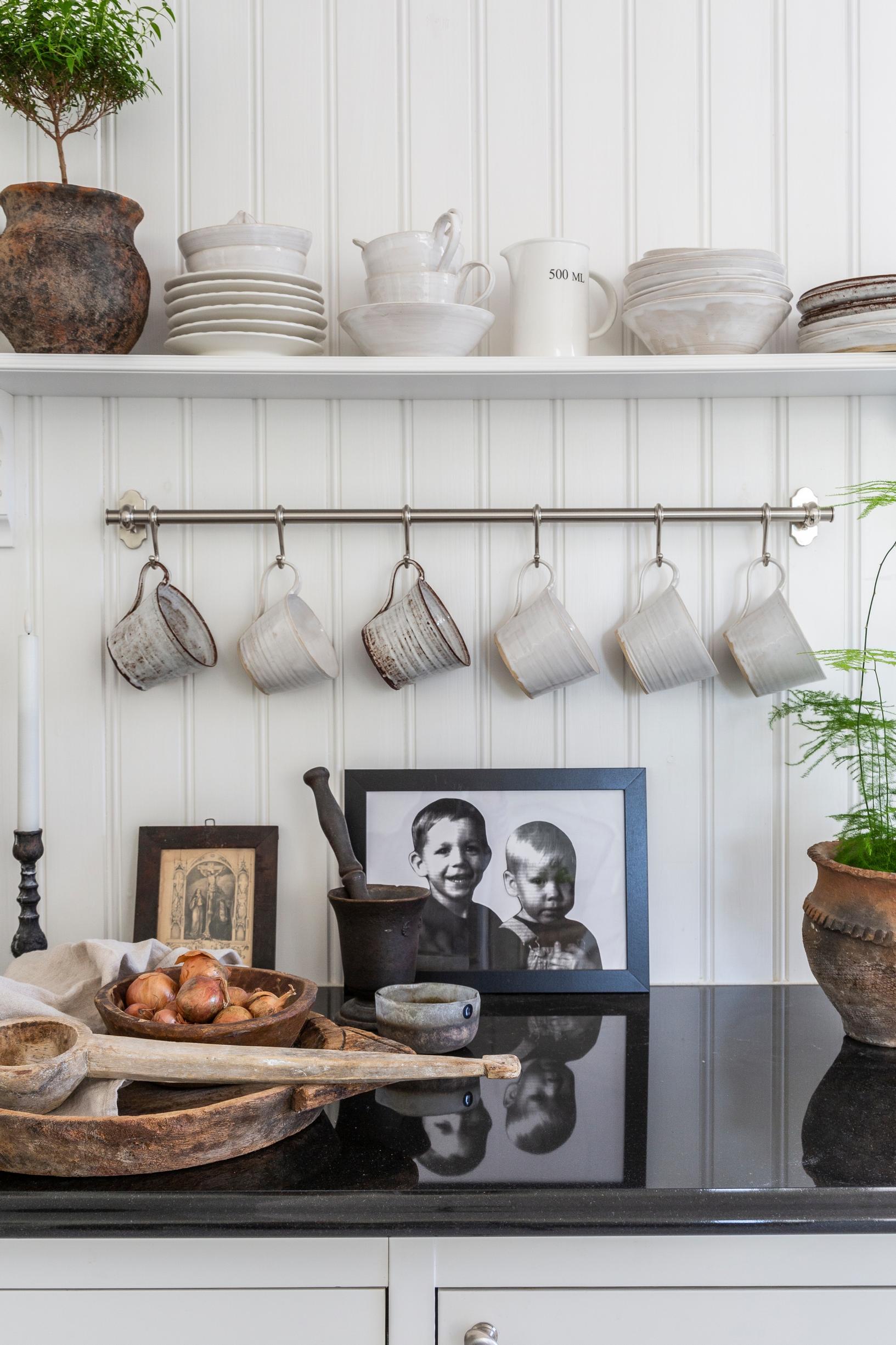 Kitchen with photos and dishes on a hanging rail and open shelf