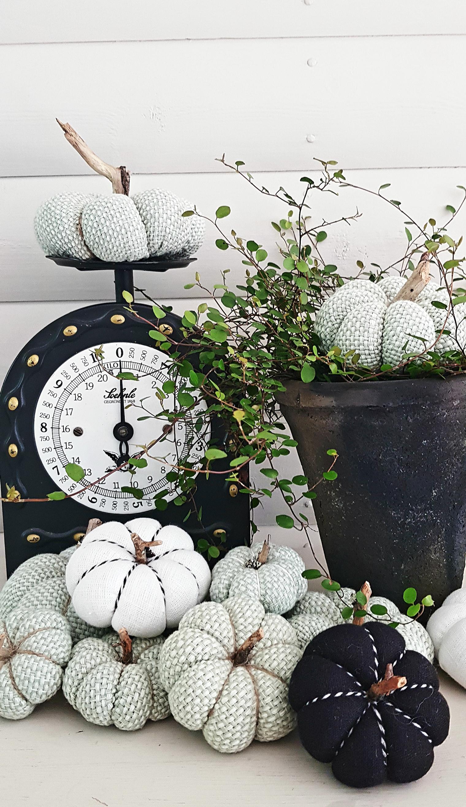 A black fabric pumpkin among light-colored ones.