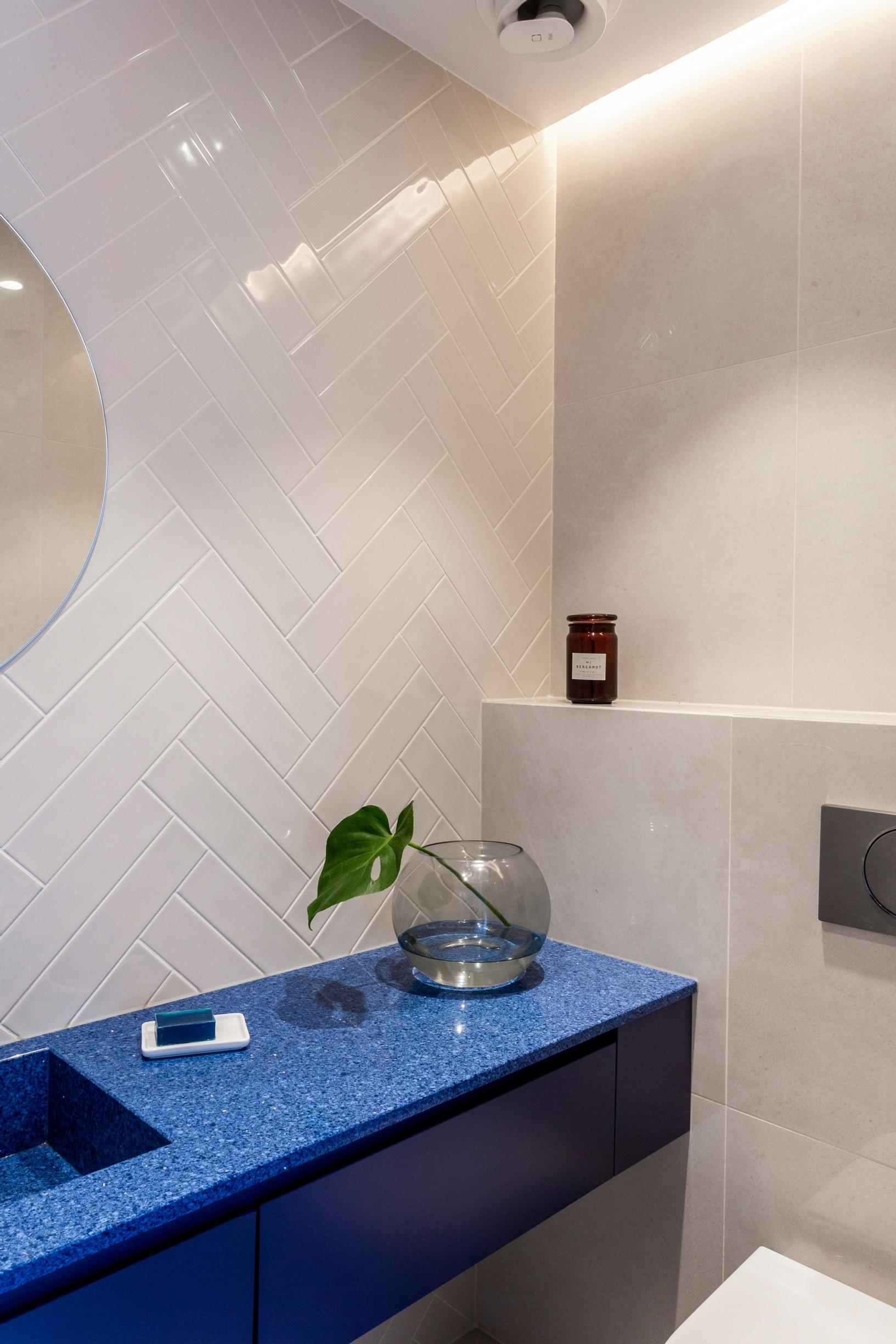 Bathroom featuring blue vanity units and herringbone tile patterns