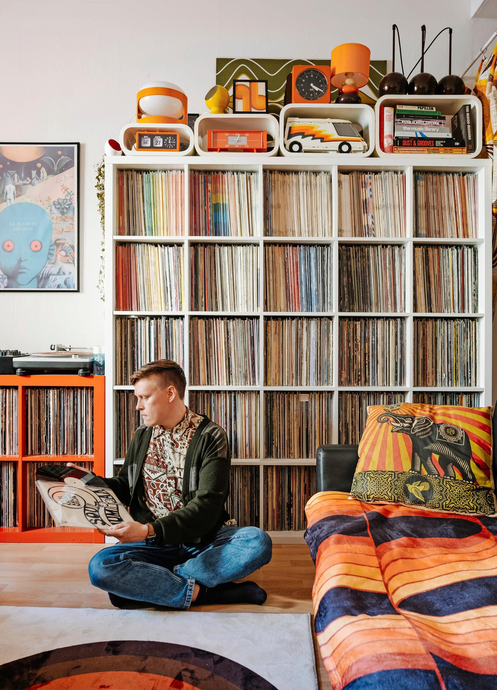 Photo of a man sitting on the floor in front of his record collection.