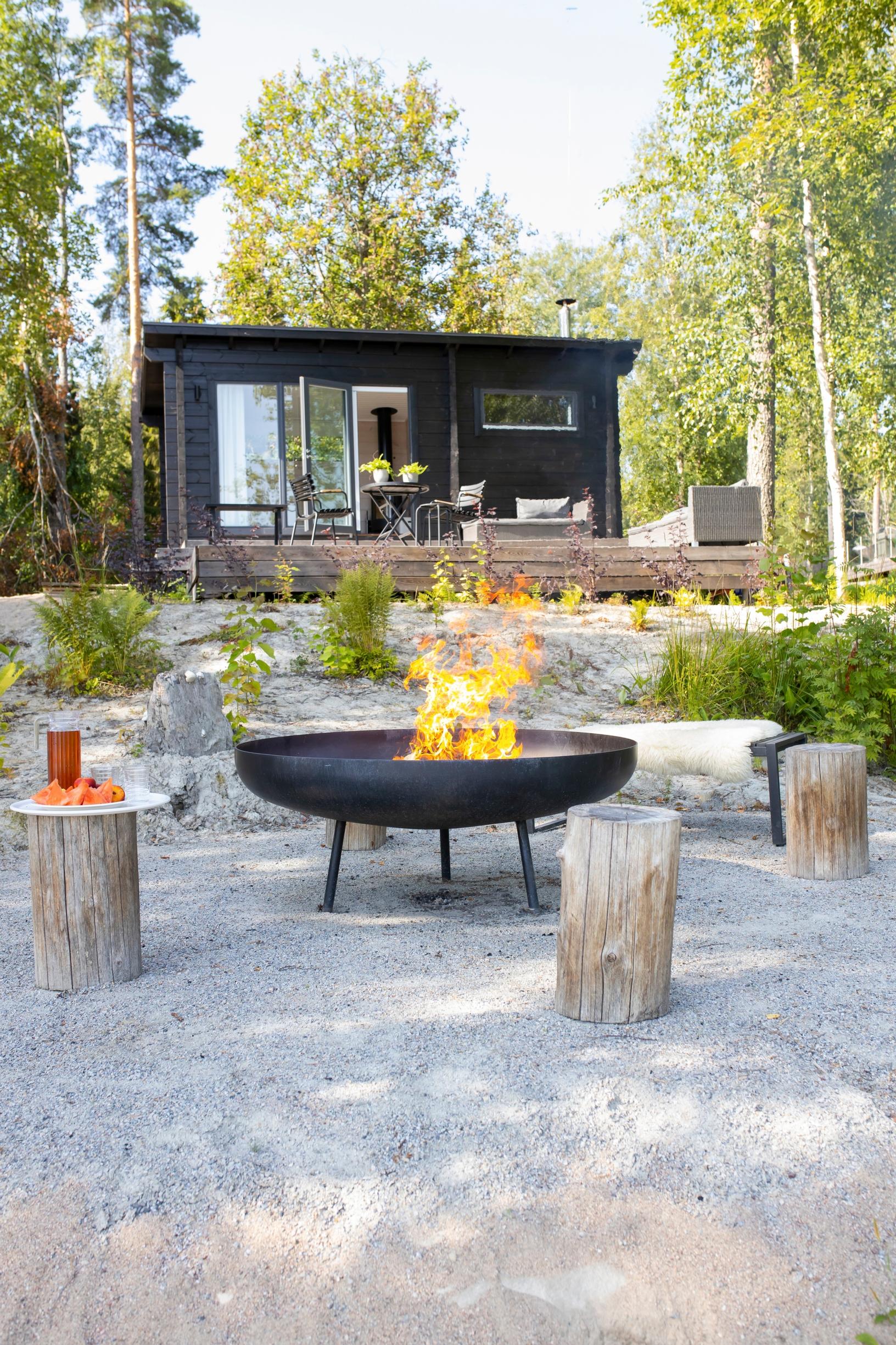 A modern fire pit in the garden of a black cottage