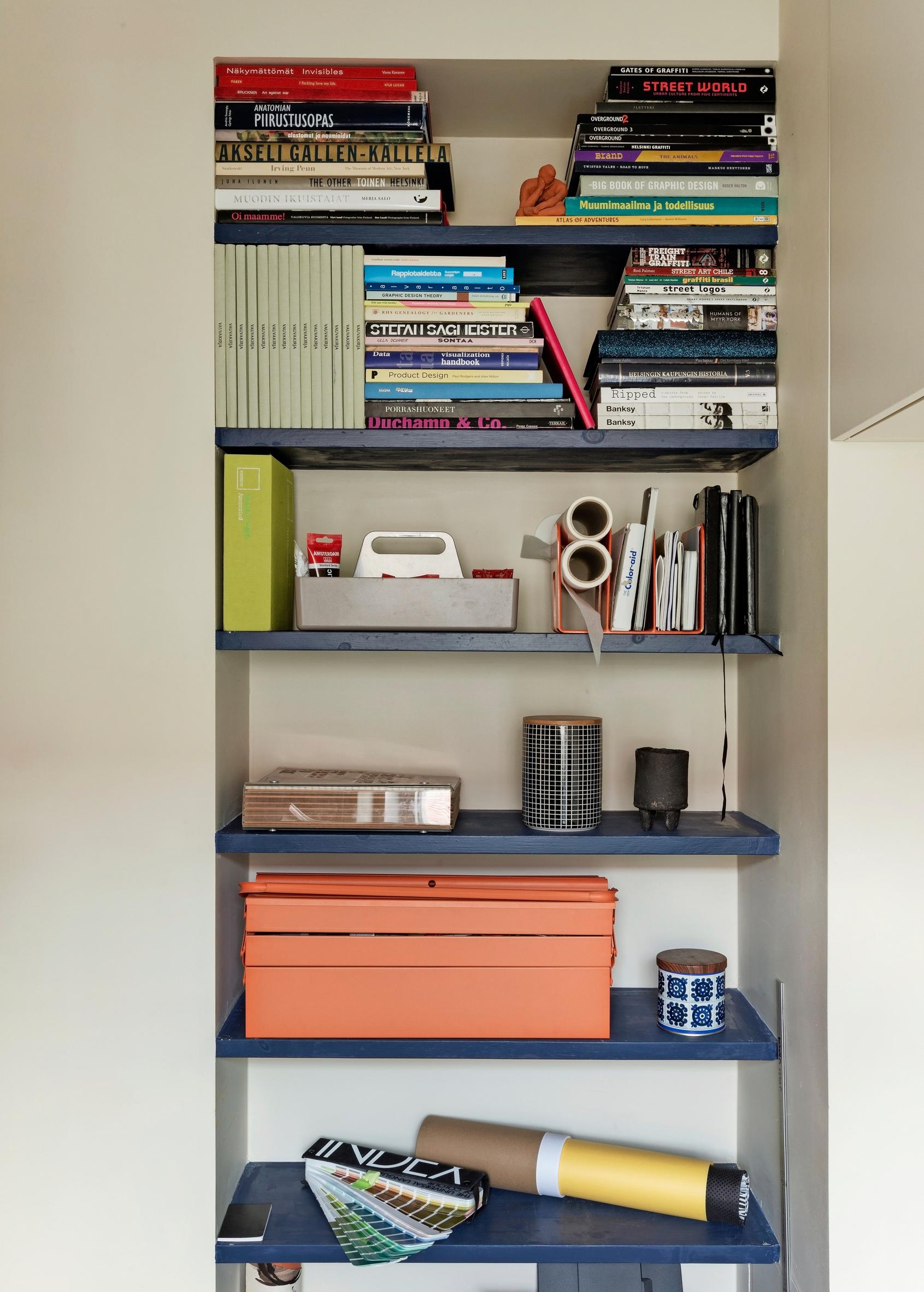 The blue open shelves in the workspace fill the gap left by the old fridge.