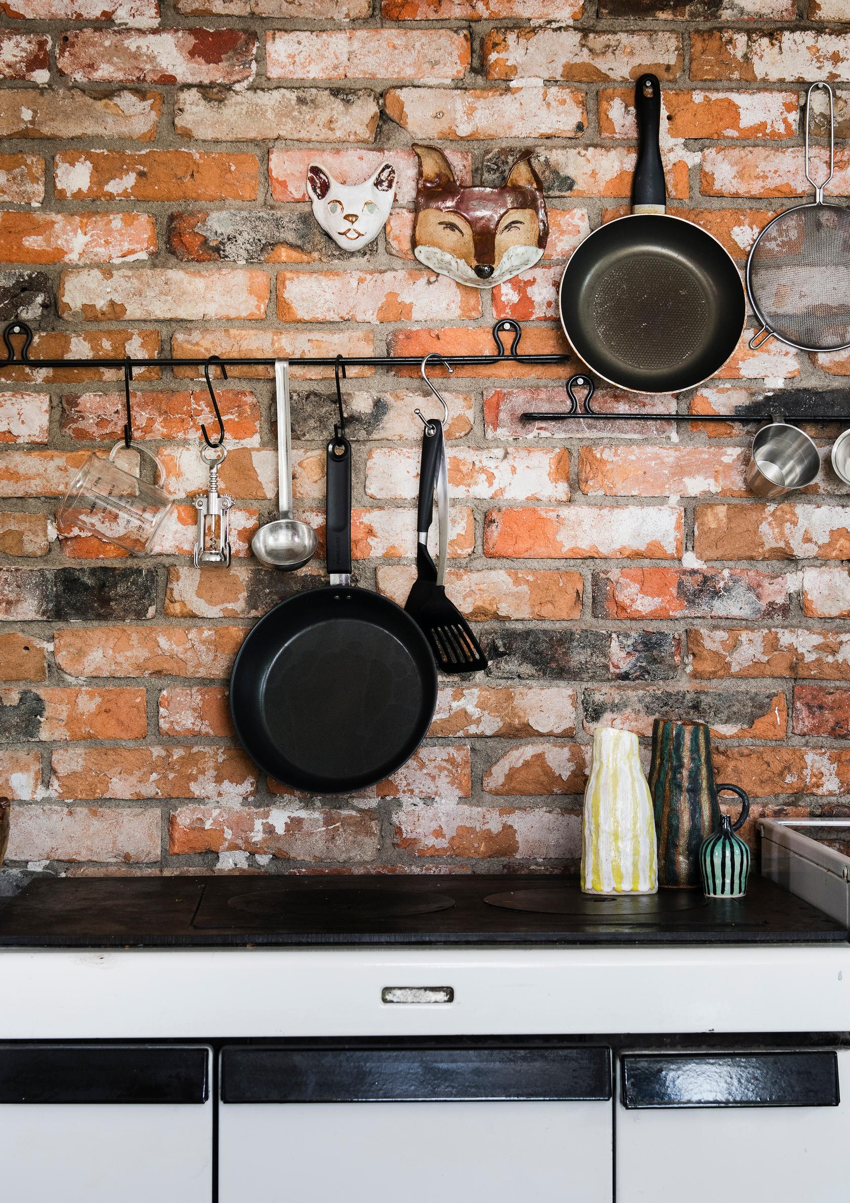 Brick wall in the kitchen with a rail for kitchen utensils