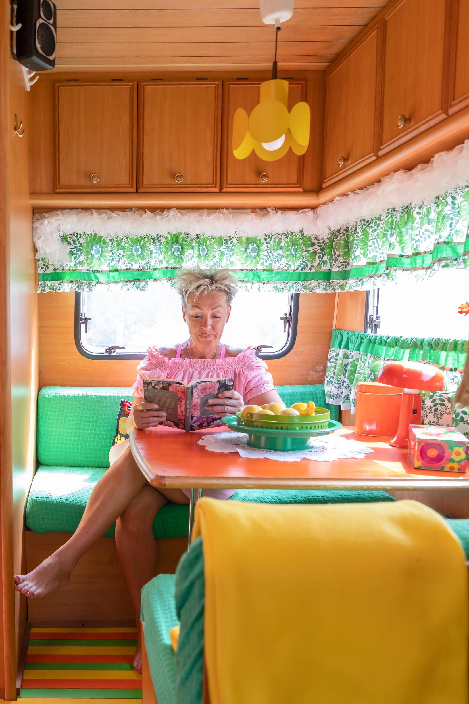 Kirsi Niiranen reading at the table inside the travel trailer
