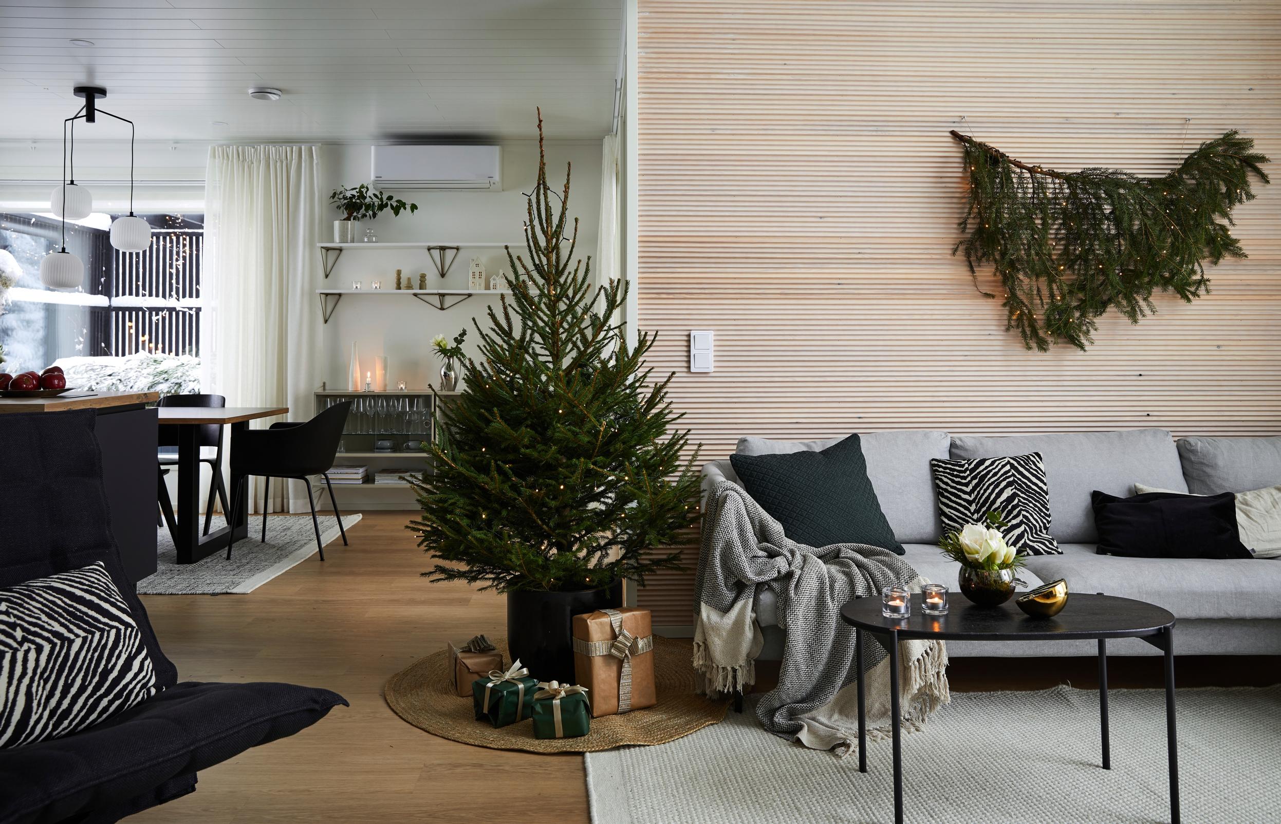 Christmas tree, sofa, and coffee table in the living room, and a conifer decoration on the wall