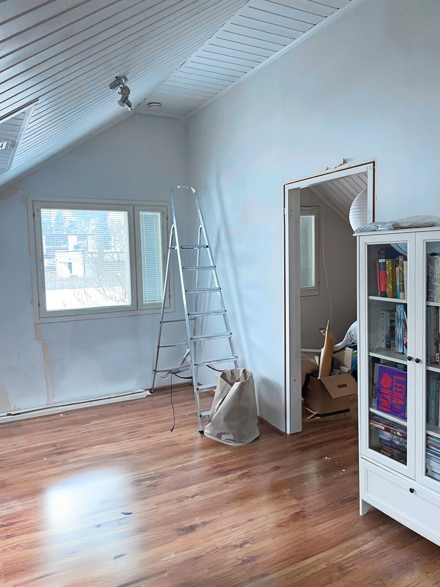 An open door from the landing leads to the bedroom. There is an A-frame ladder in the window corner.