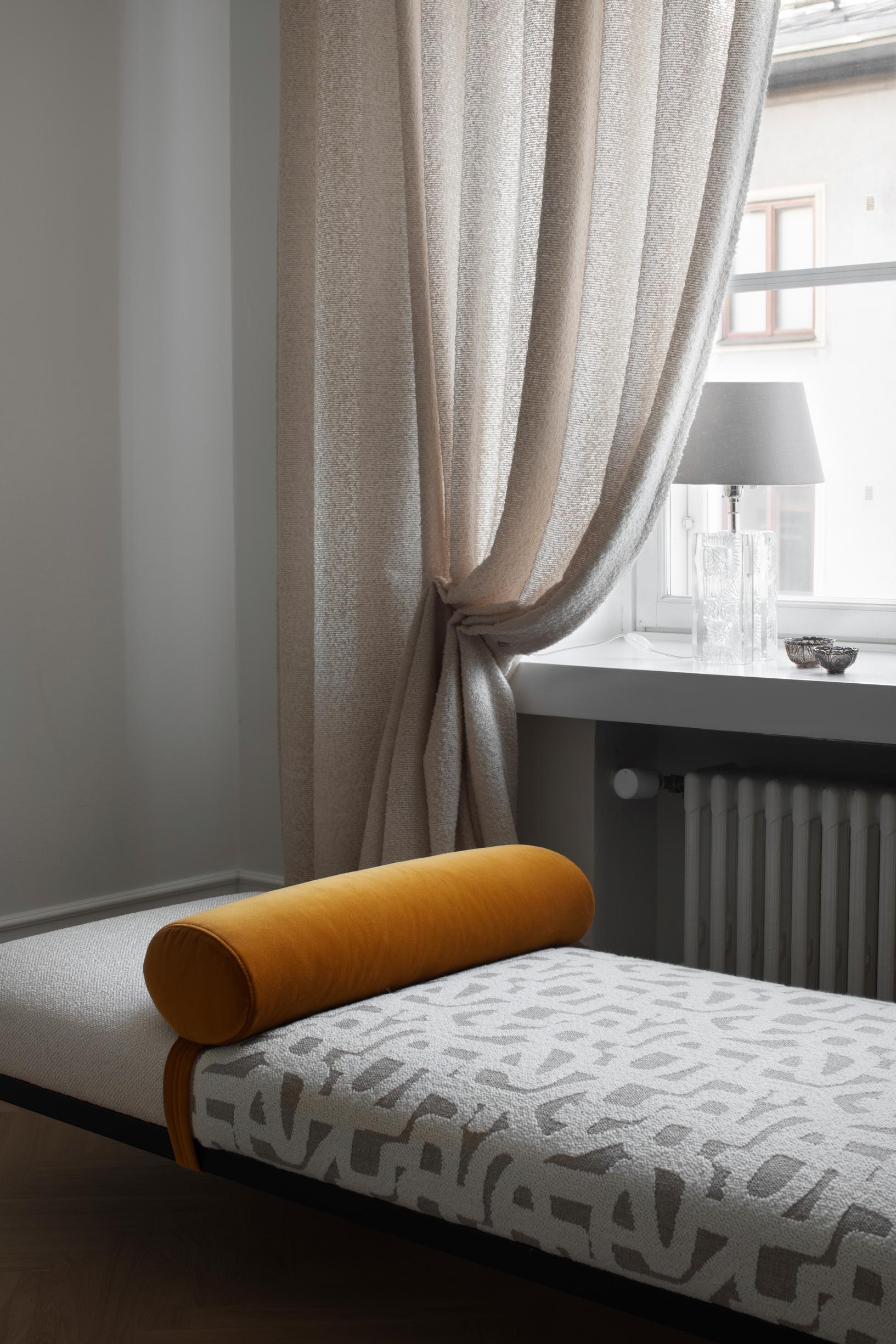 Adea daybed in front of the window and draped curtain.
