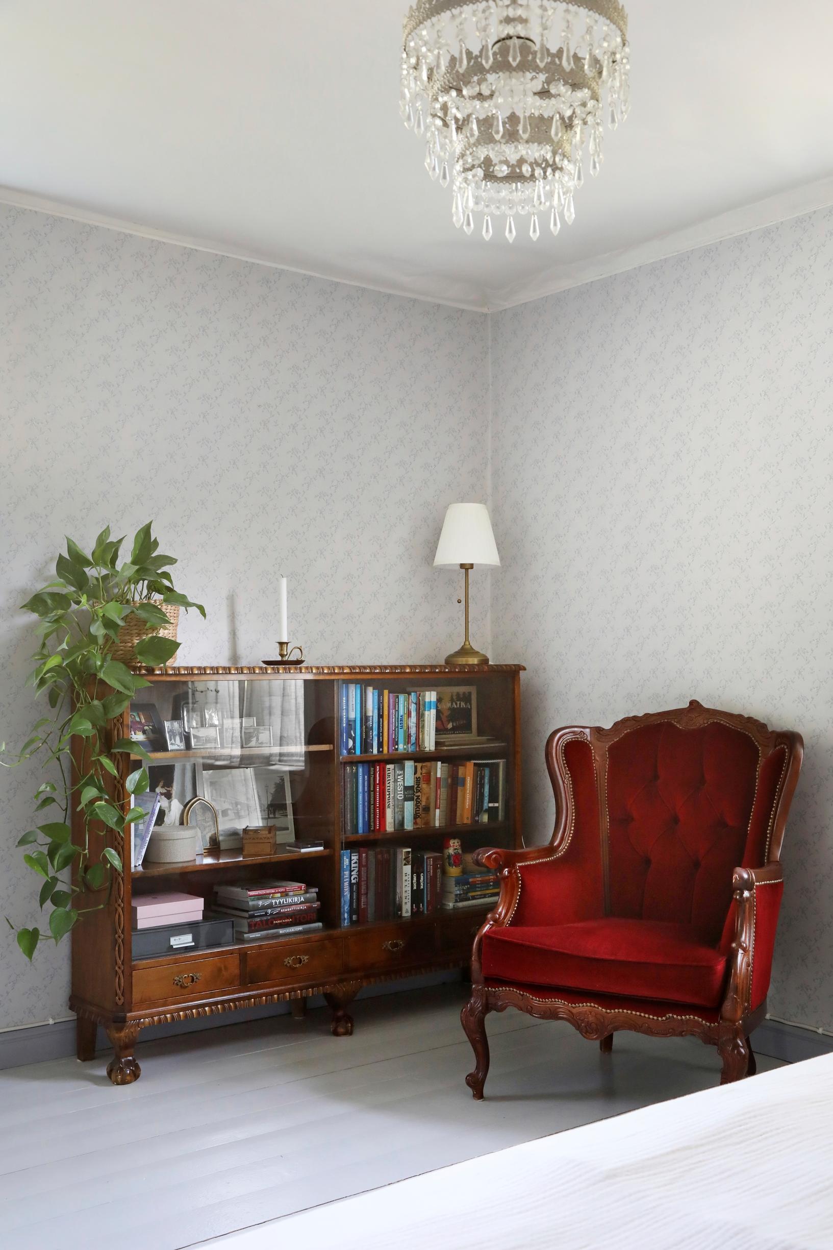 Sideboard, books, houseplant, table lamp, and old red armchair