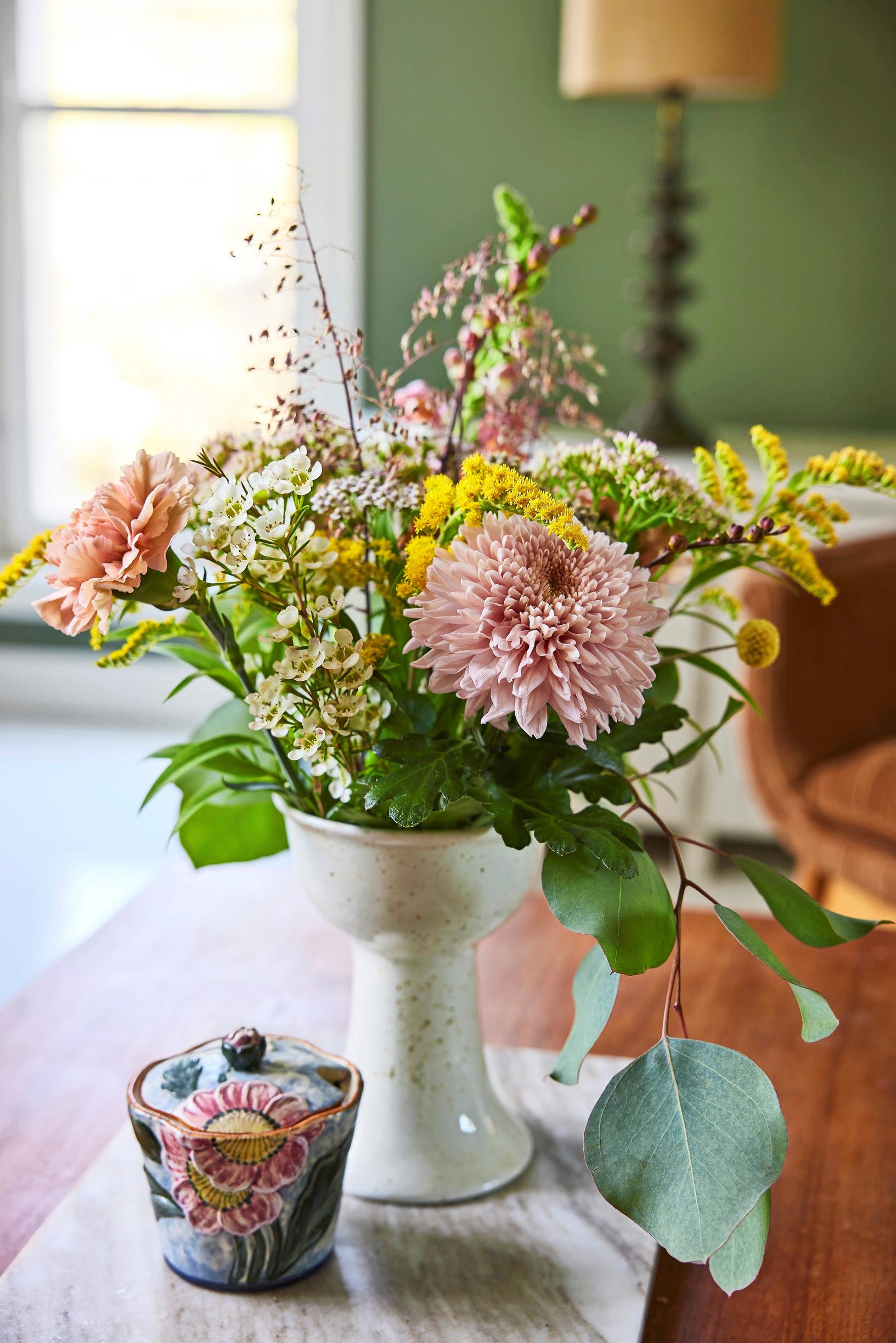 a colorful bouquet in a light-colored vase on a marble slab, plus a small bowl