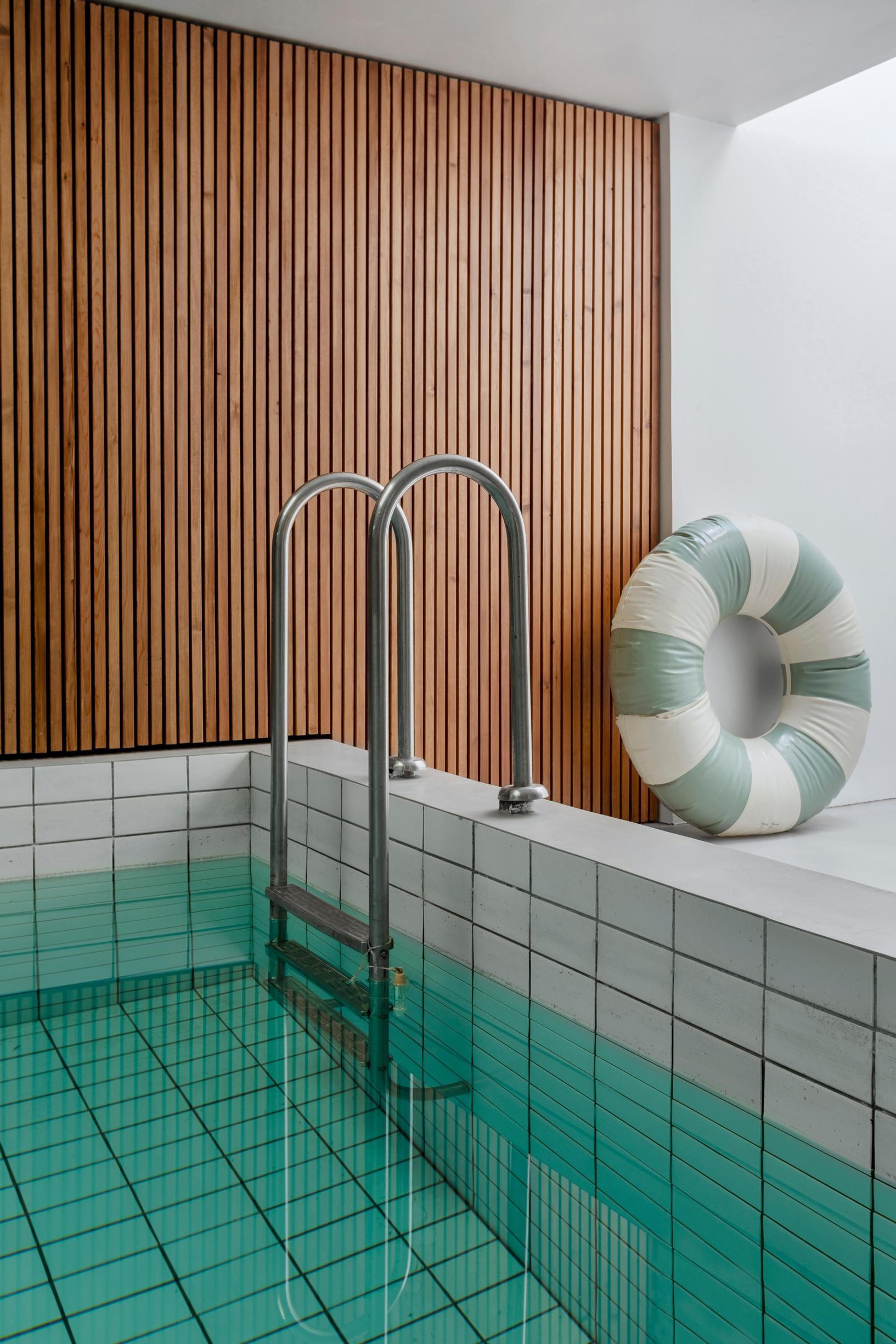 A wooden slatted wall adds warmth to the swimming pool room