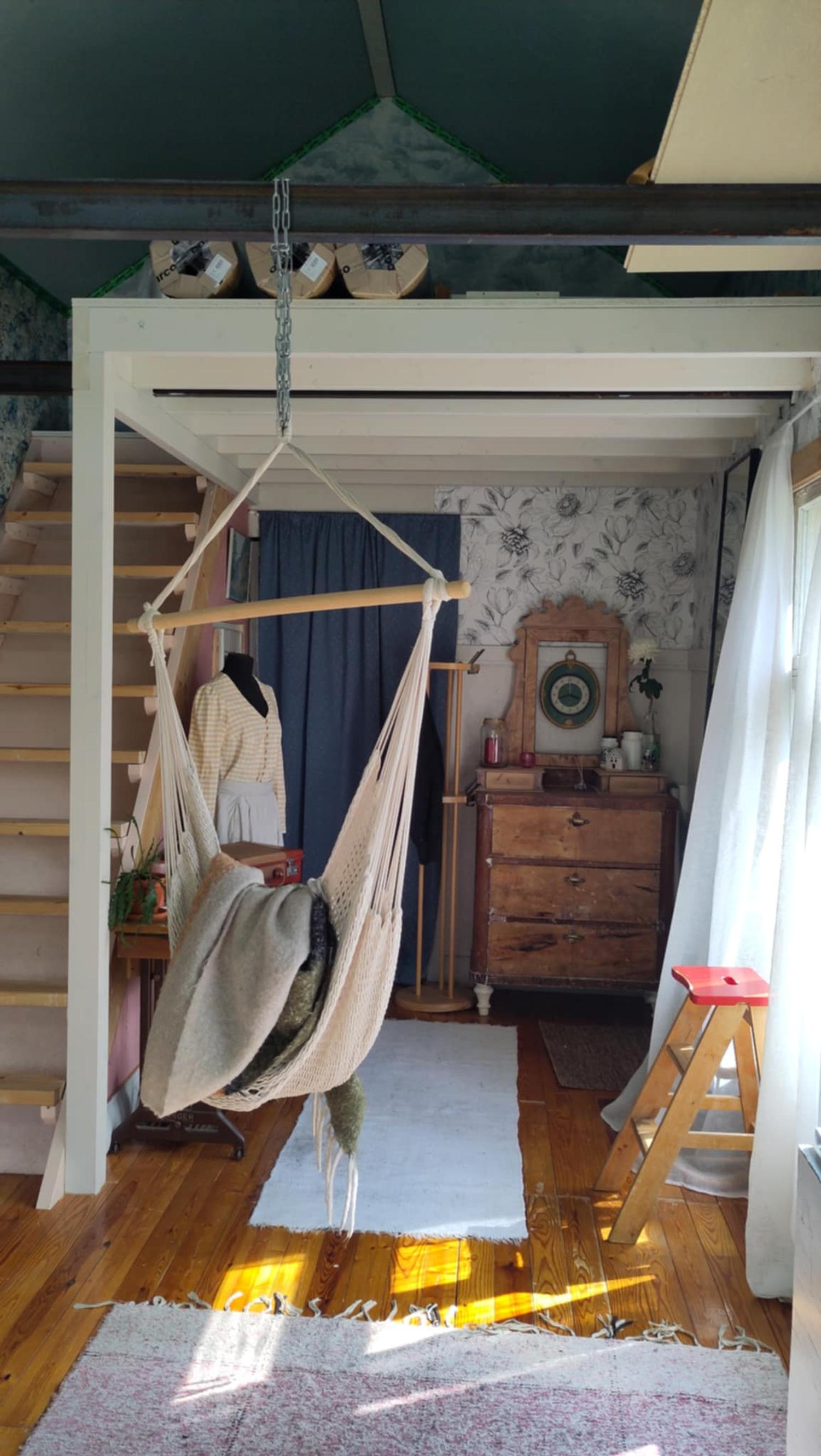Stairs to the sleeping loft line the left wall, and a hanging chair dangles from the loft into the open space.