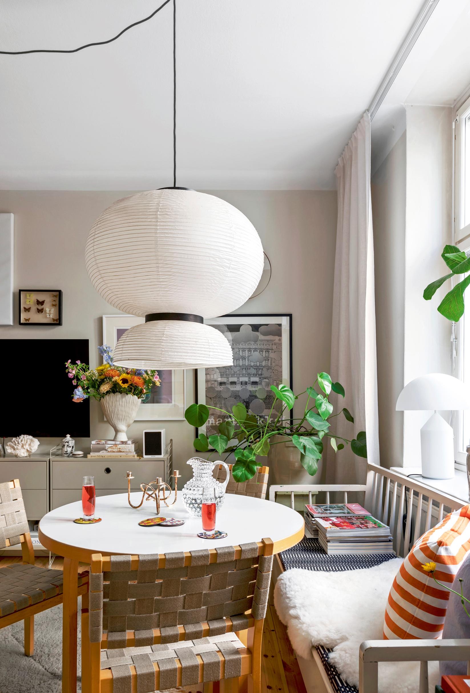 In the dining area, a large rice paper lamp accompanies the Artek table and old wooden sofa