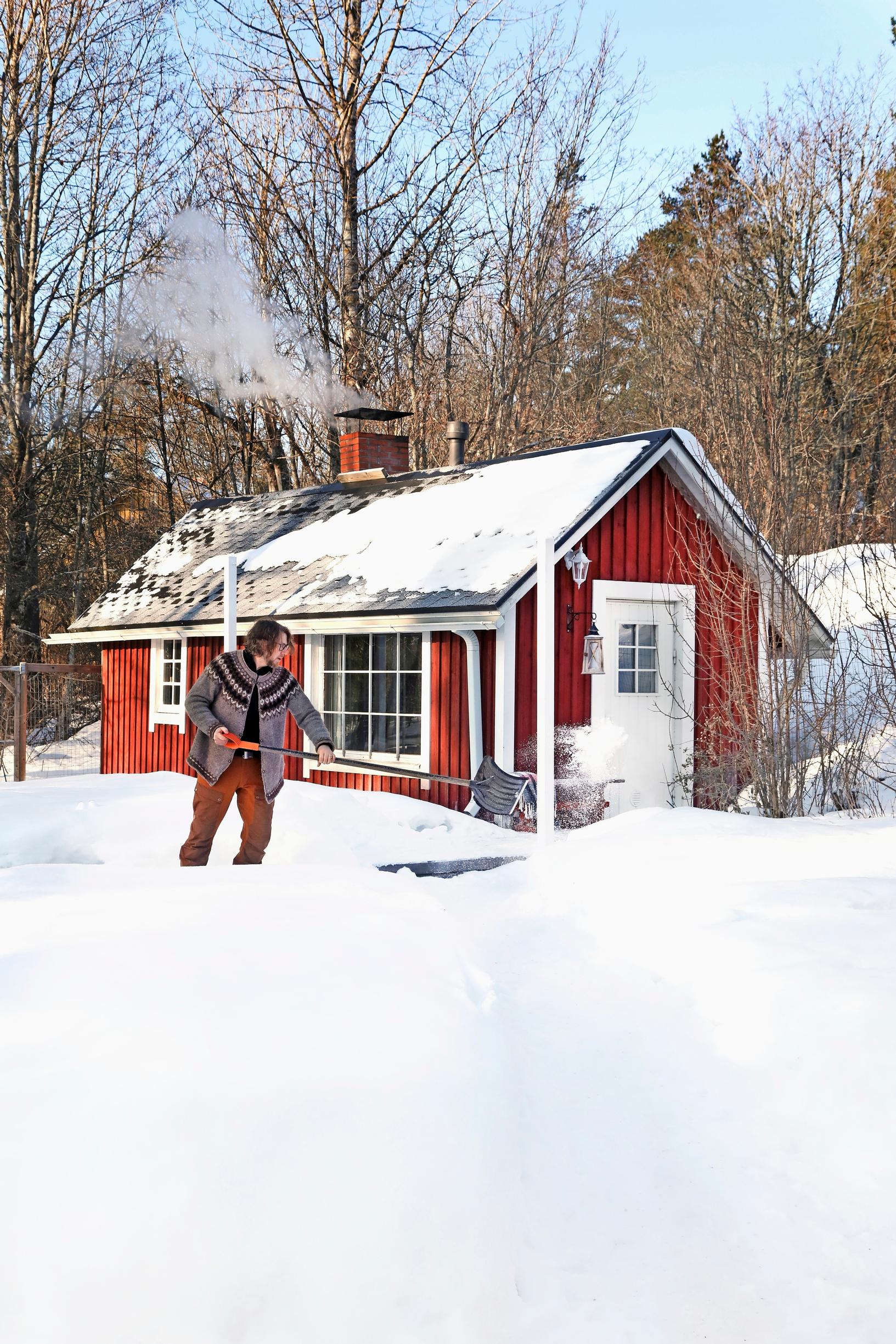 Robert Hole shovels snow in front of the sauna