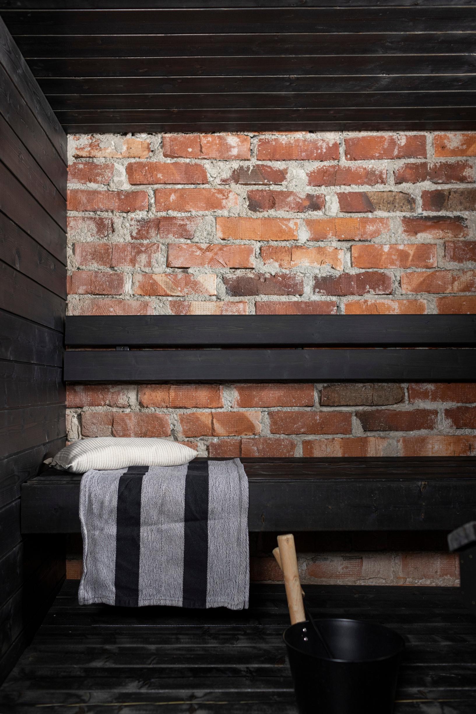 Brick-walled sauna with black benches