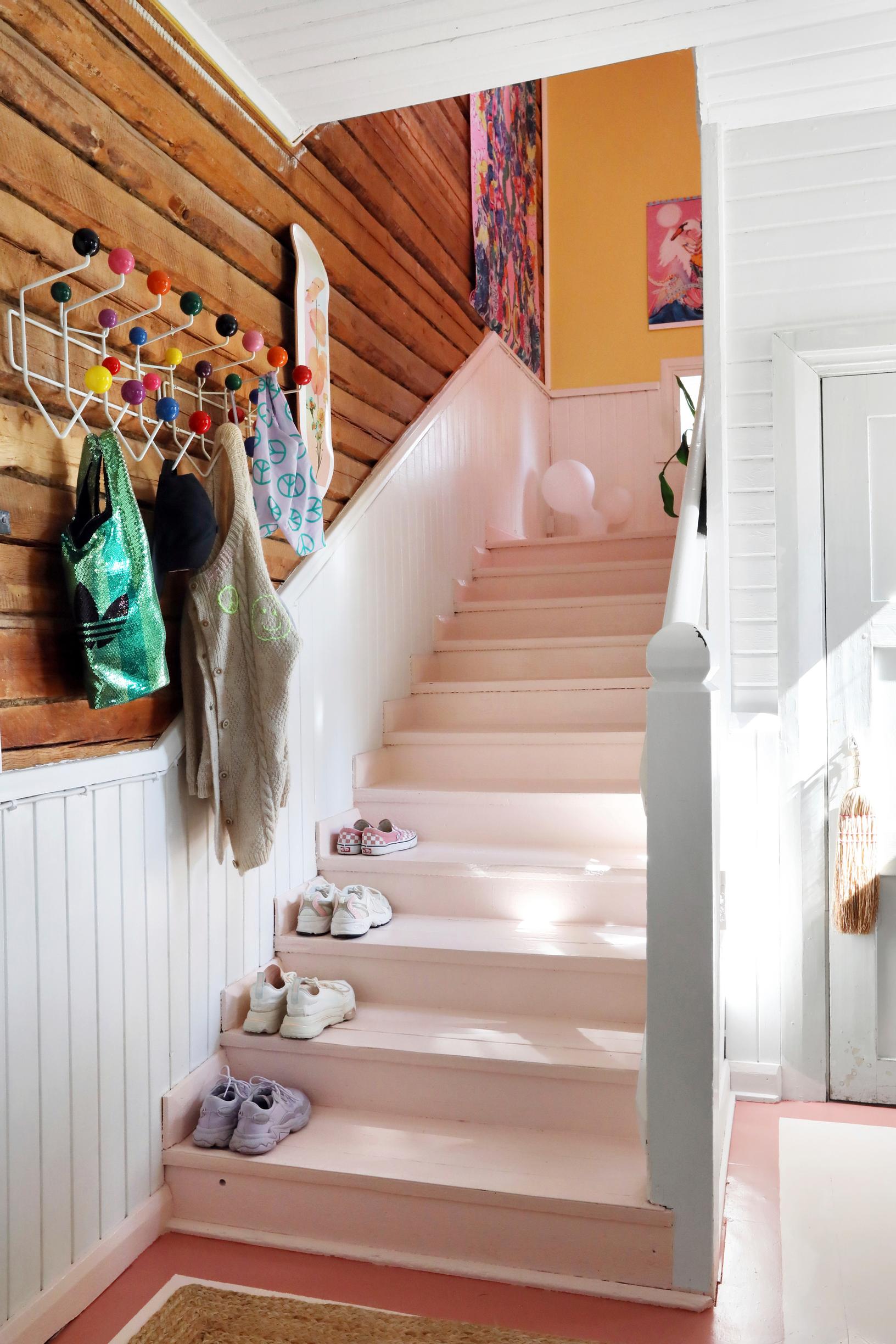 A colorful coat rack at the bottom of the stairs.