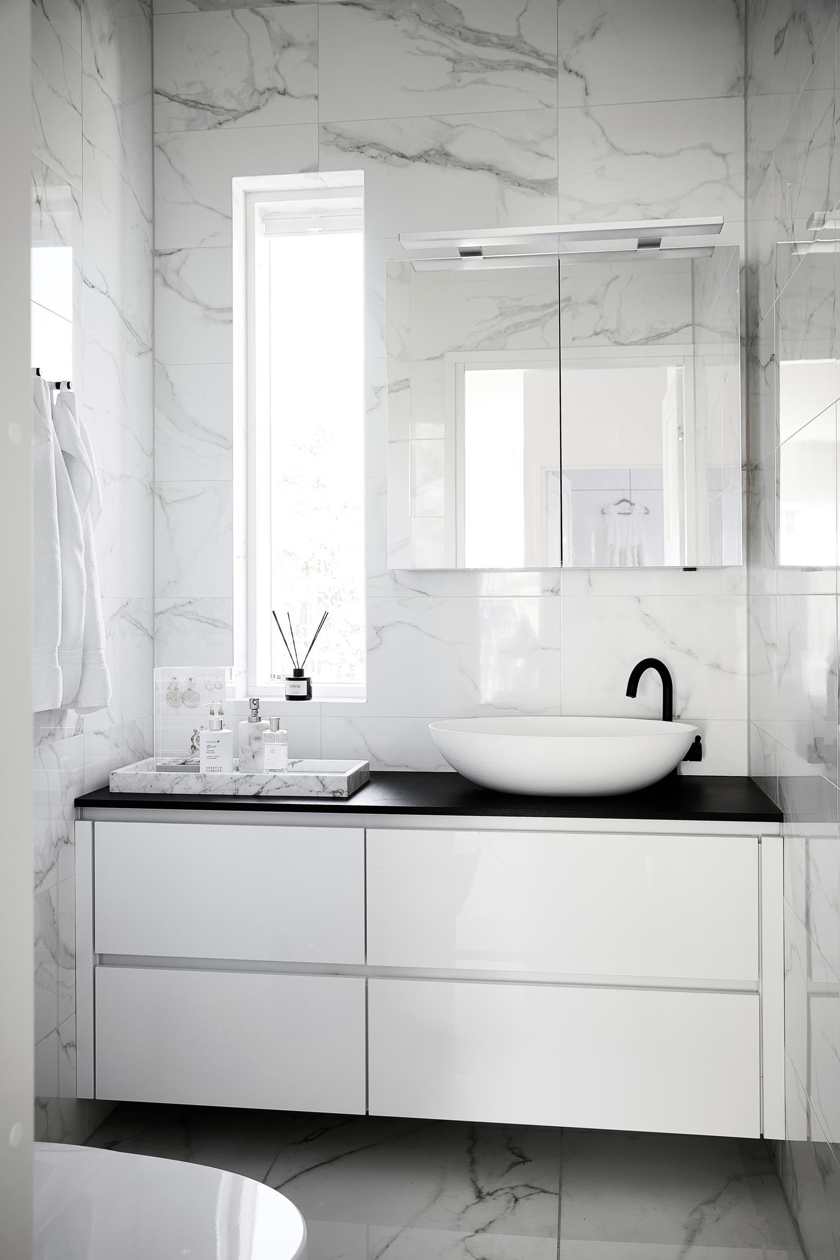 A bathroom with white fixtures and tiling.