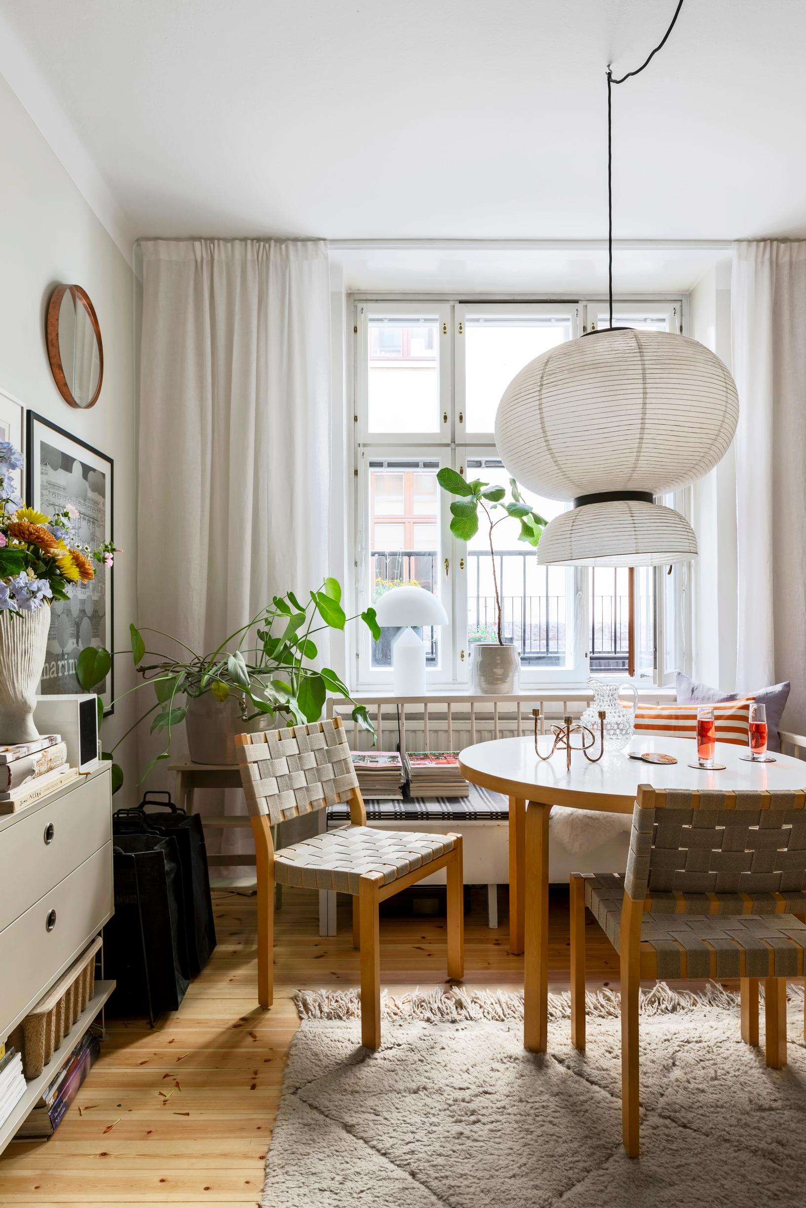 An old wooden sofa by the window in the dining area pairs with an Artek table and chairs