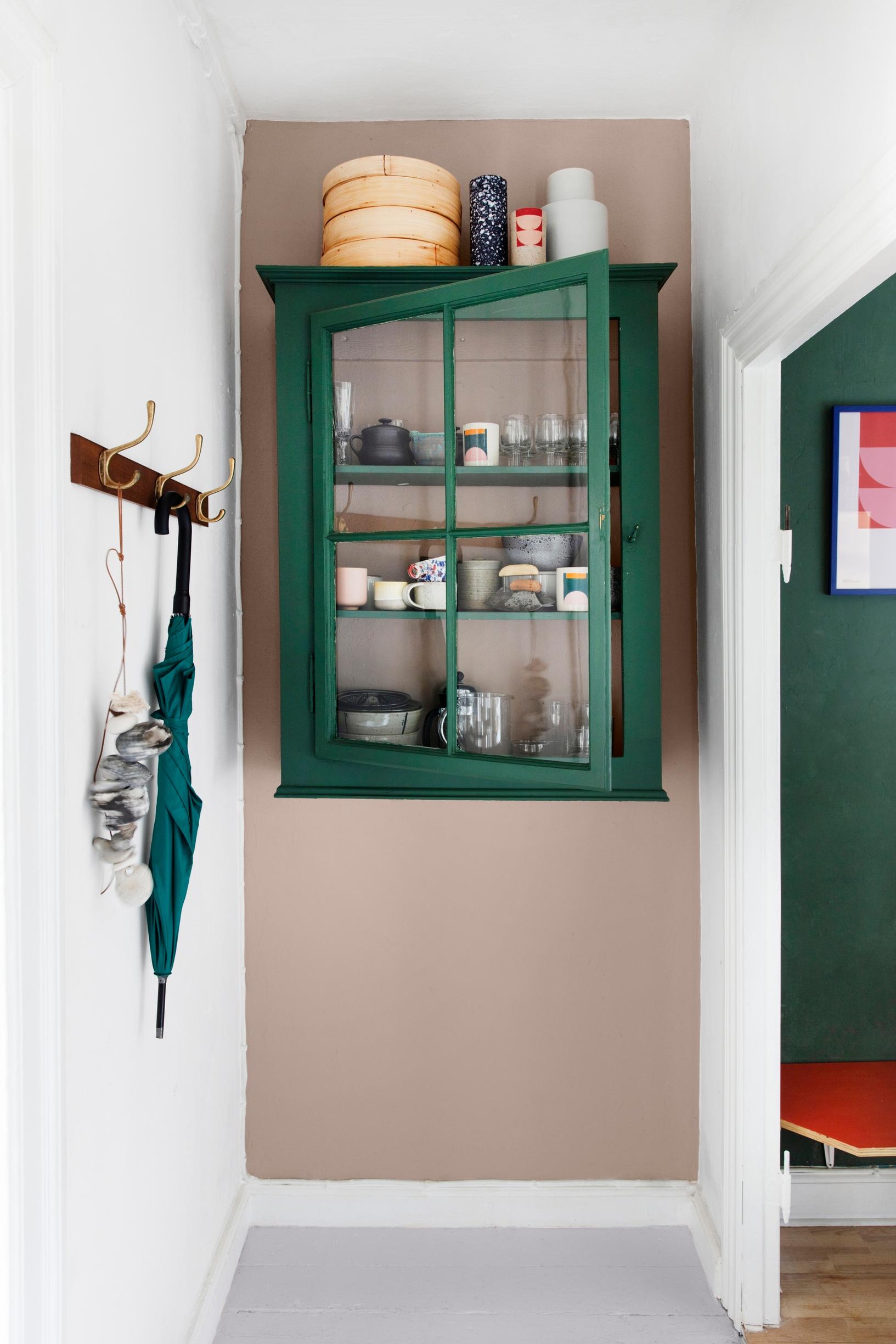 A repurposed display cabinet painted green in a hallway.