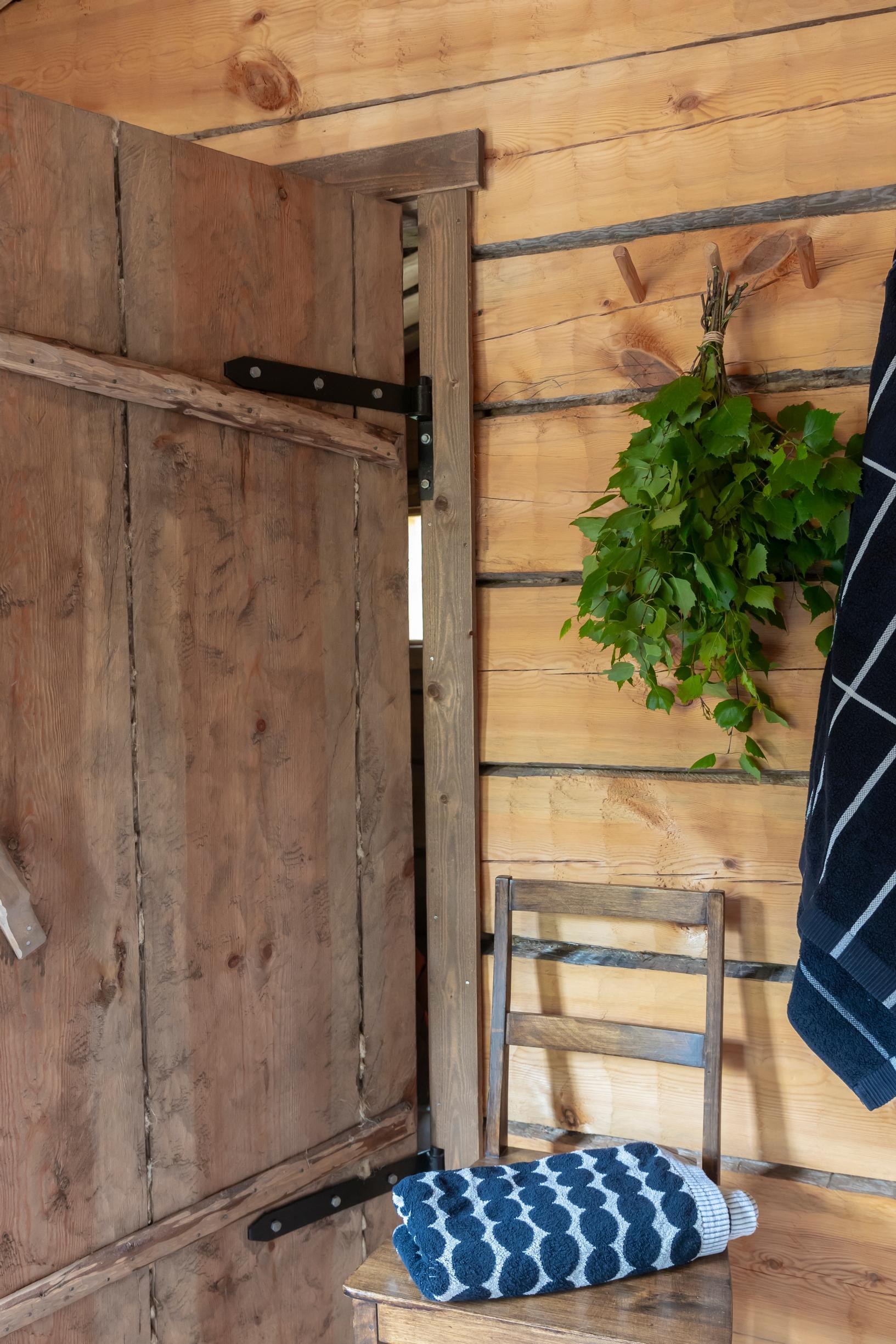 a birch whisk on the wall and a chair in the sauna's dressing room