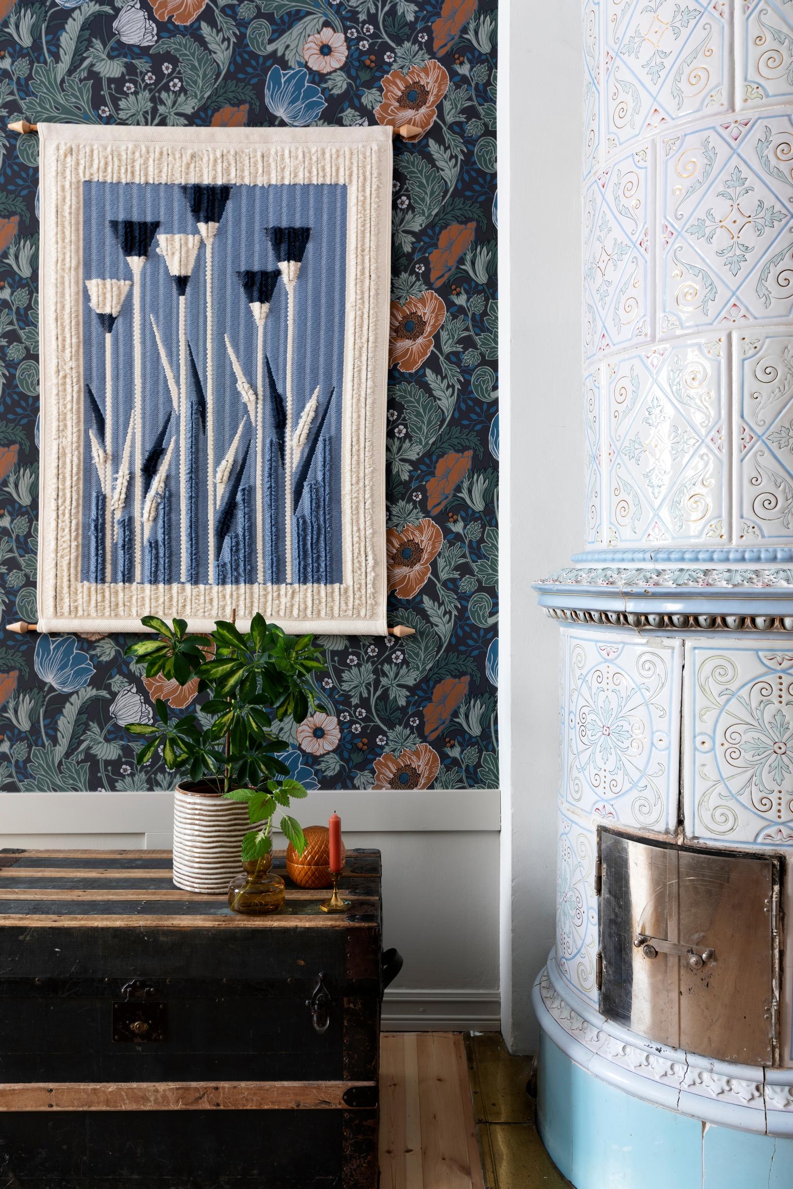 A tapestry and a trunk next to the tiled stove