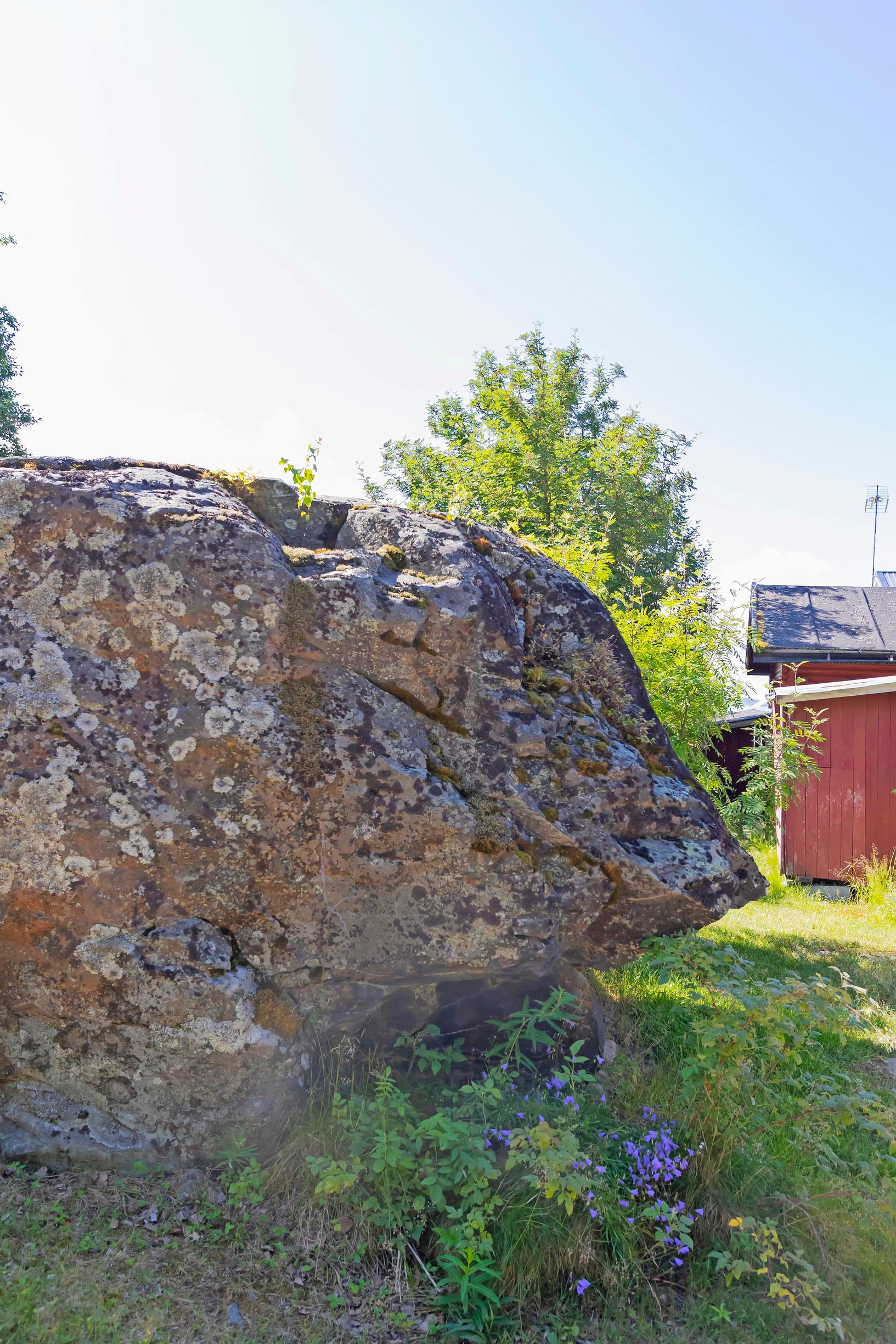 a large rock and a red building
