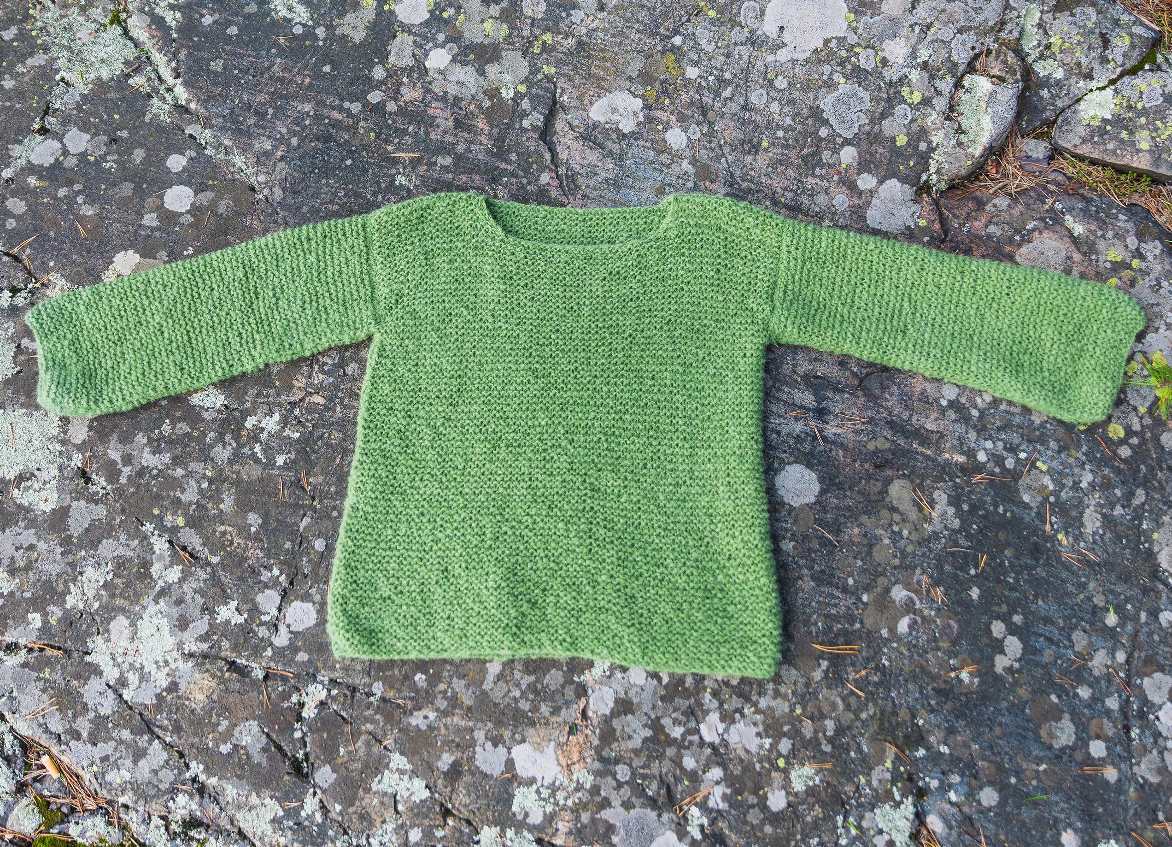 Aina sweater photographed on a rock