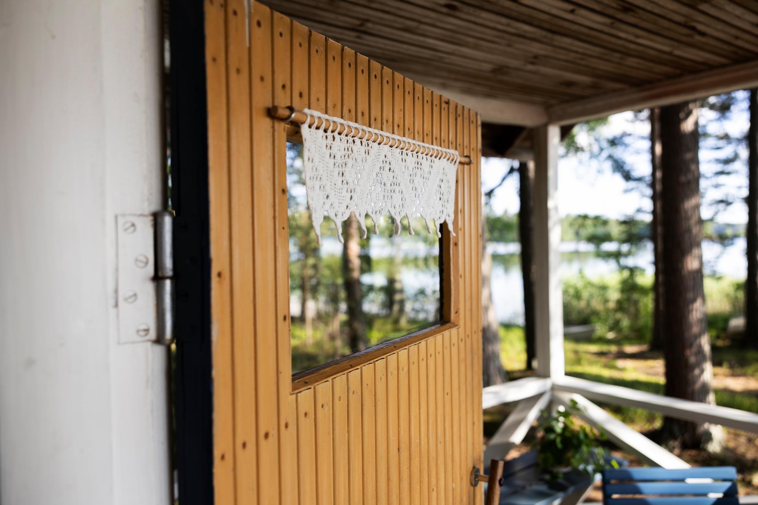 Lace curtain in the cottage's front door window, view of the lake