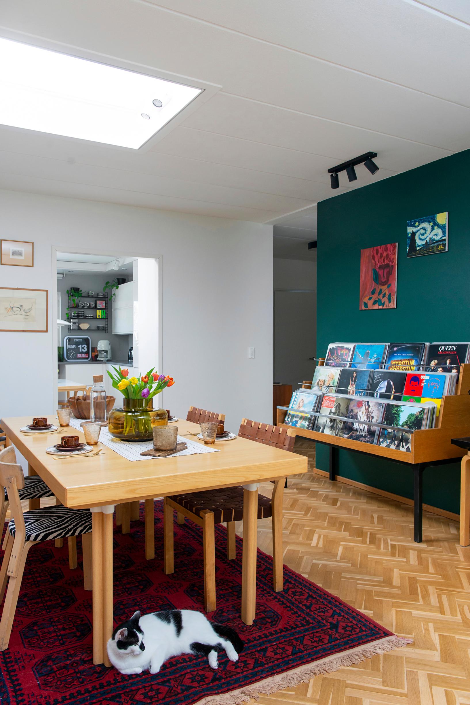 A skylight illuminates the dining area from above. The feature wall is painted bright green.