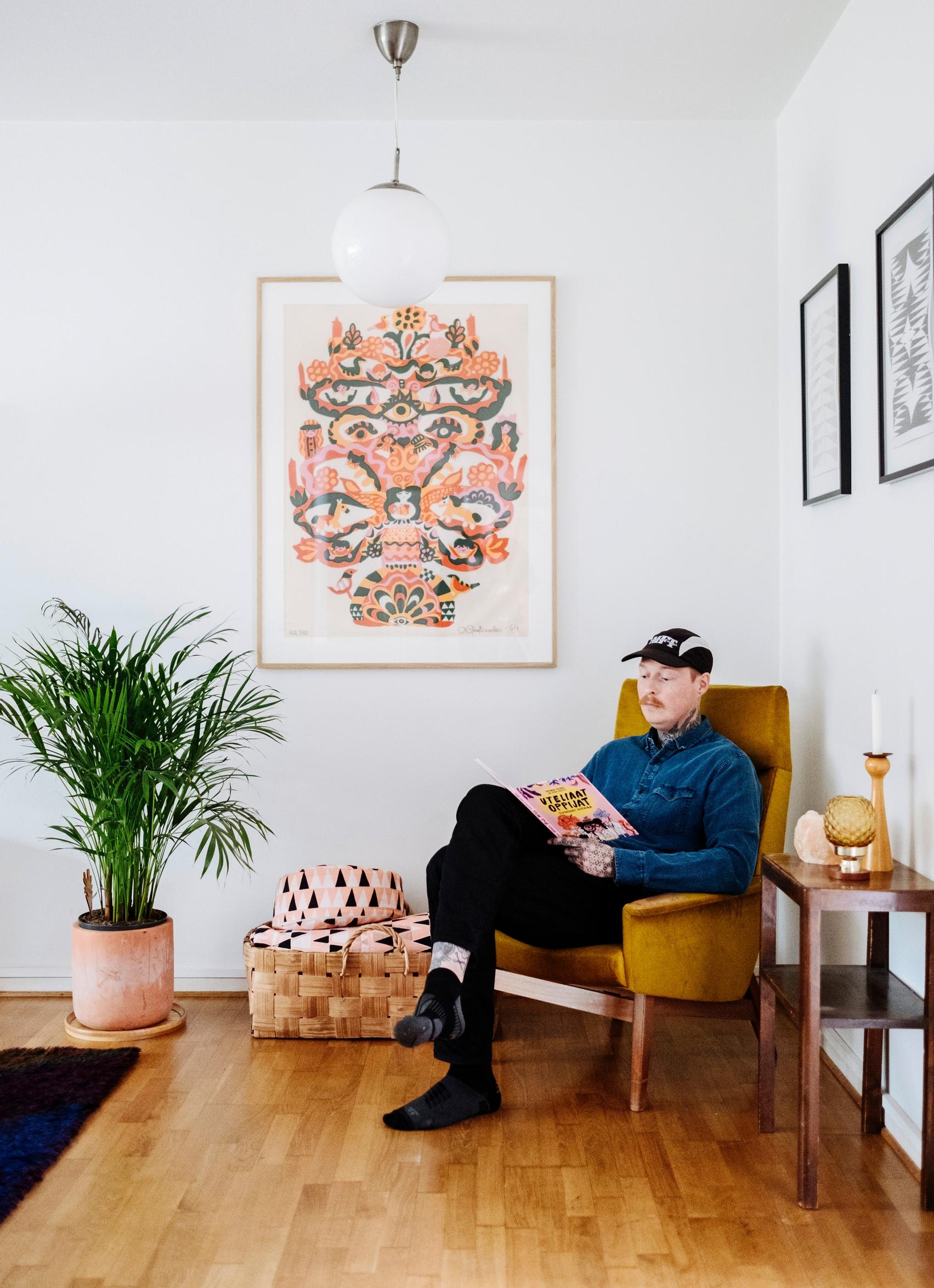 Akseli sits in an armchair in front of a colorful artwork