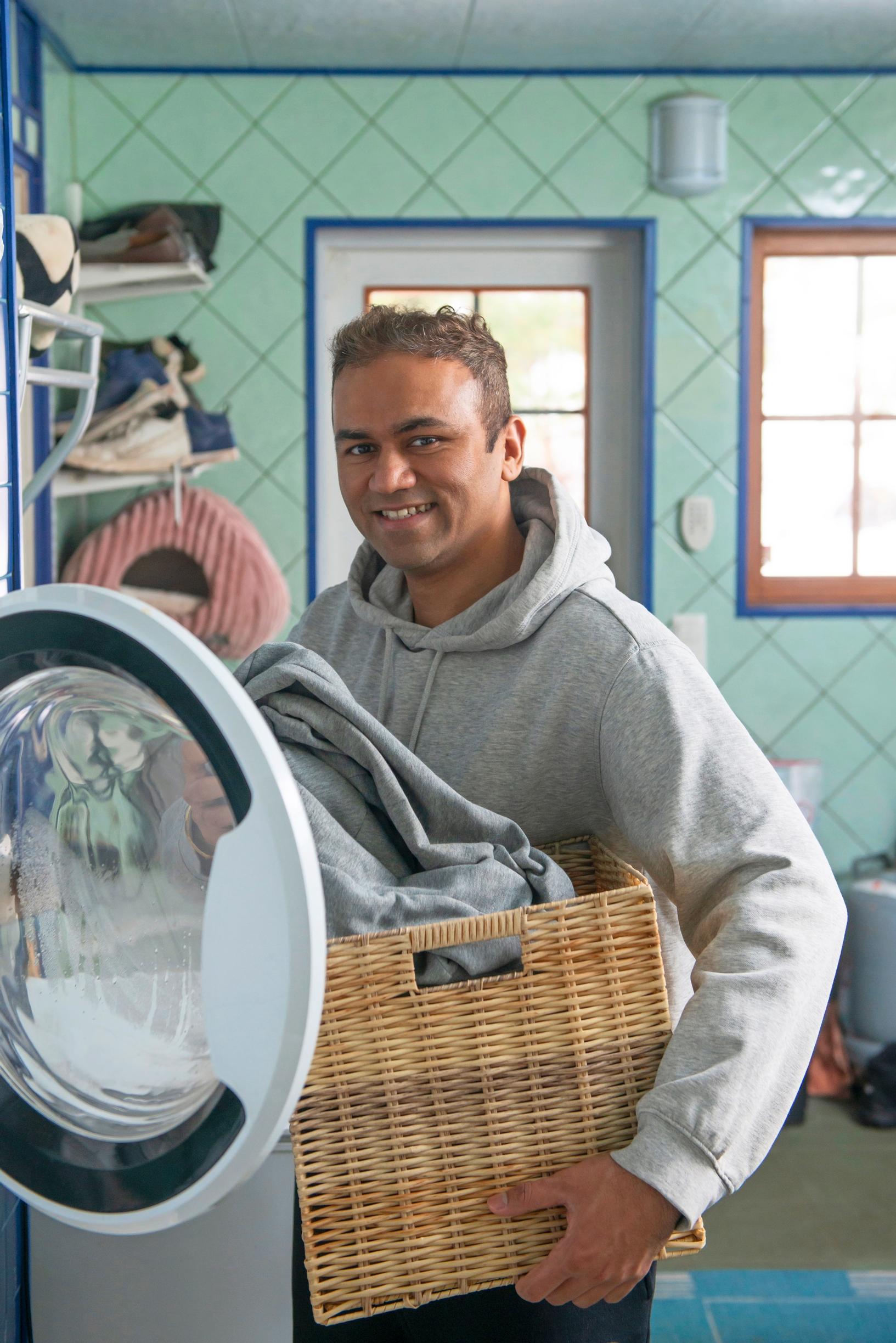 a man lifts laundry into the washing machine