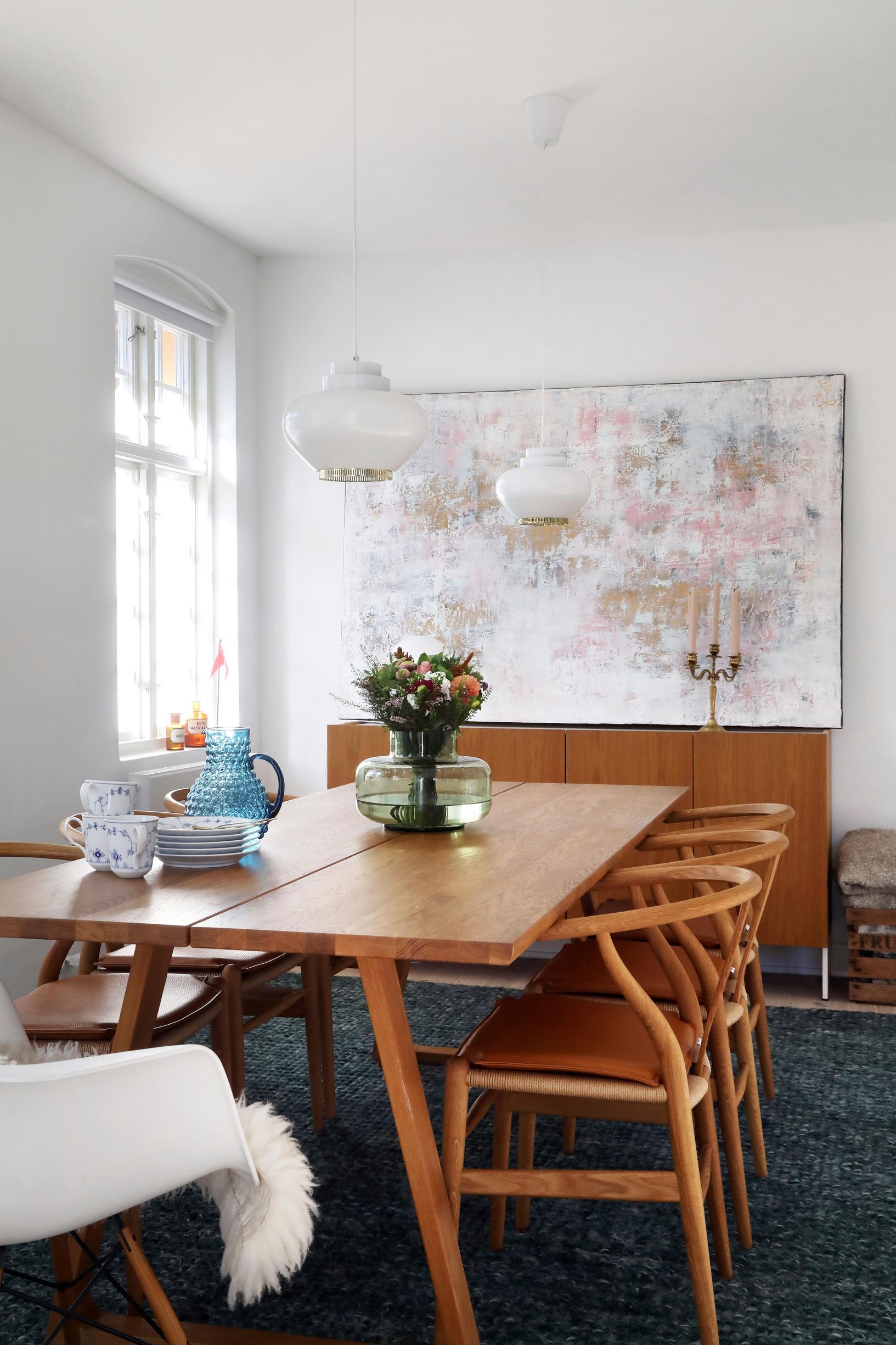 An acrylic painting by the resident, a Wishbone chair, and Artek’s “Nauris” pendant lights in the dining area