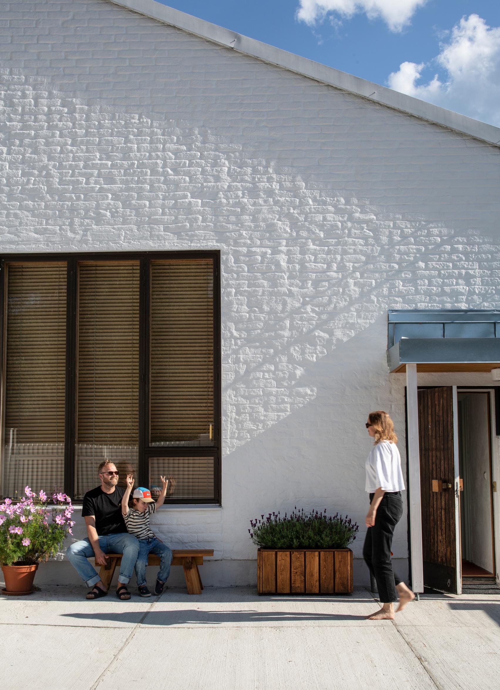 Eemil and Heini-Tuuli outside the house, summer flowers and a bench