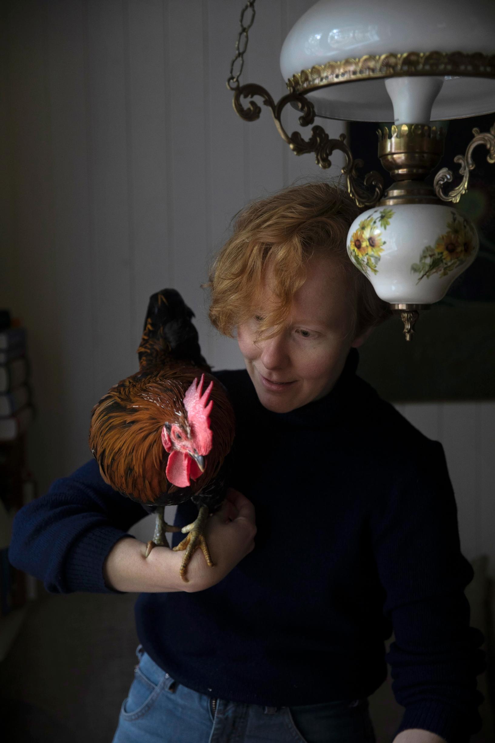 woman holding a rooster on her arm