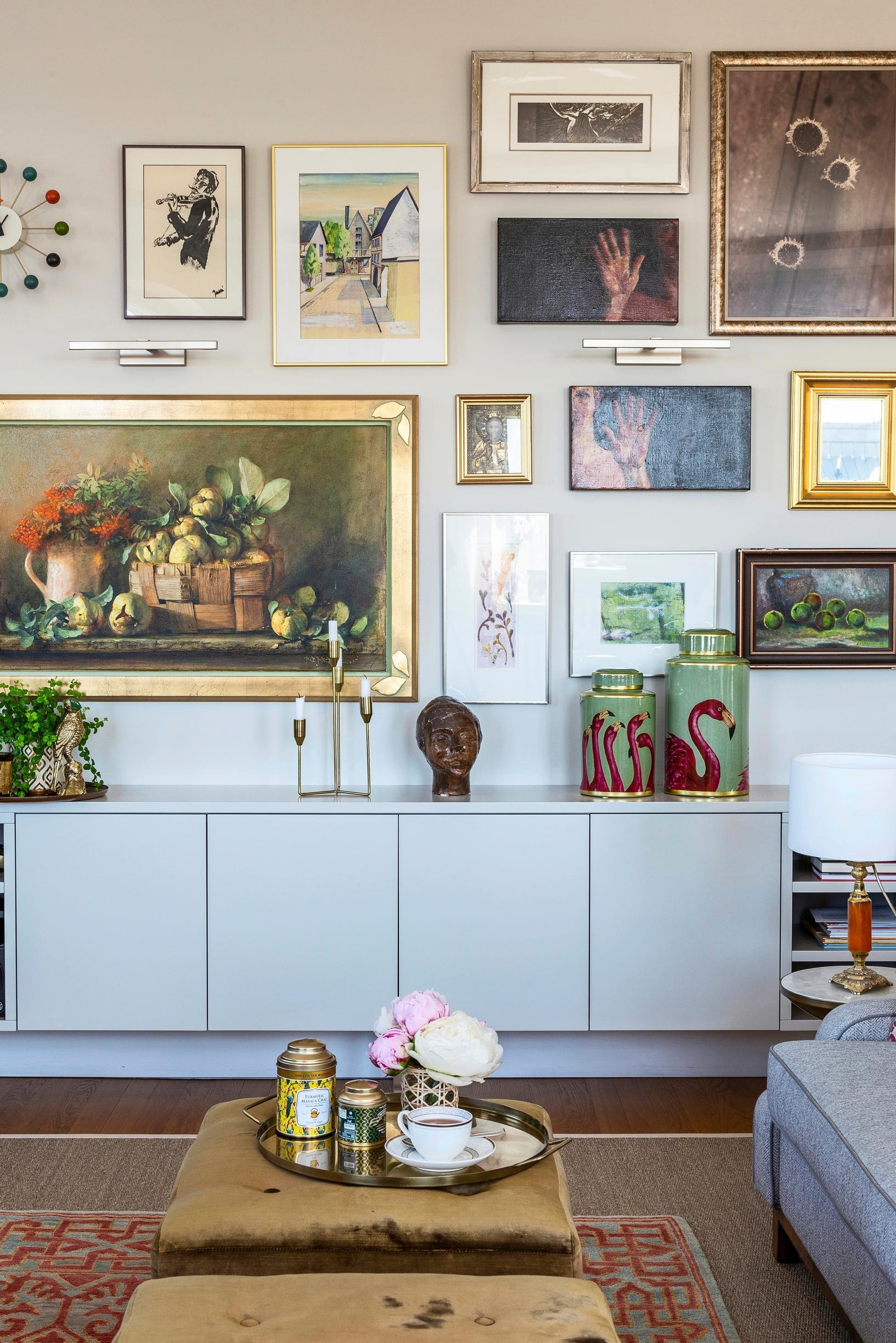 A rich collage of paintings above a sideboard