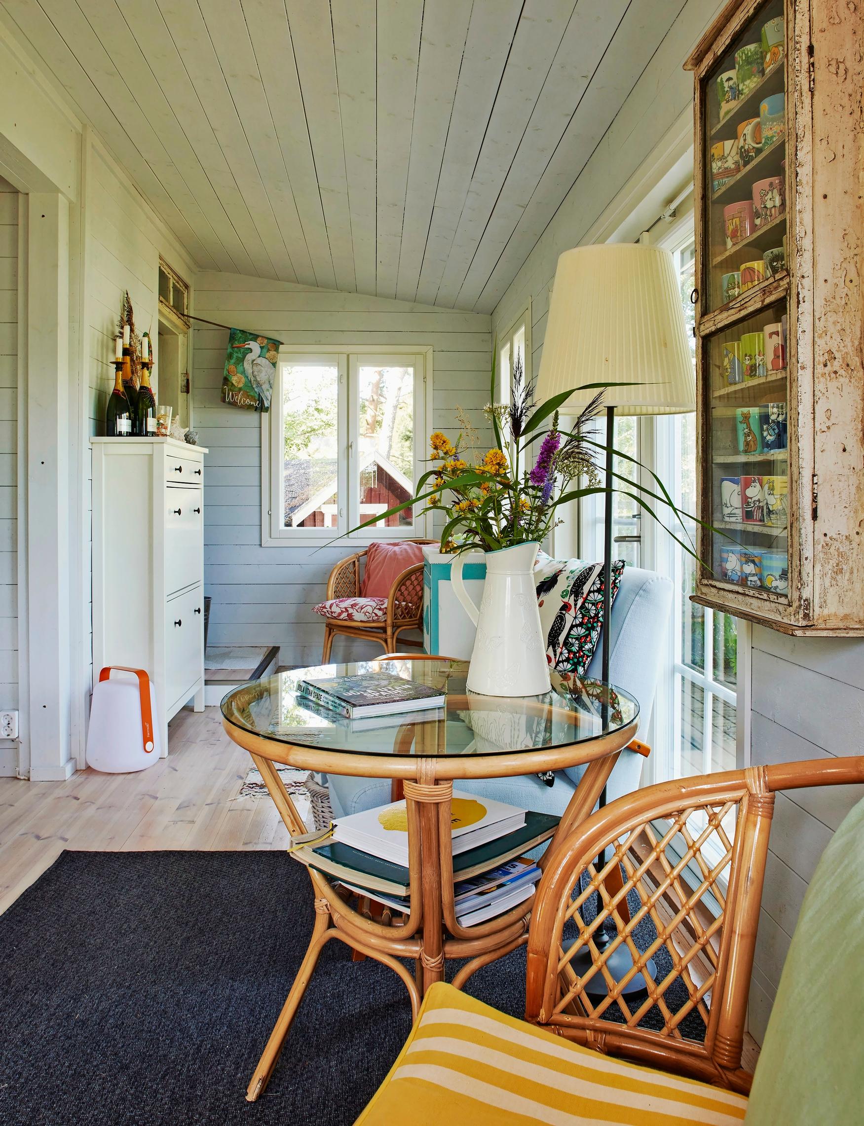 a rattan chair and table, a vase of flowers and other furniture
