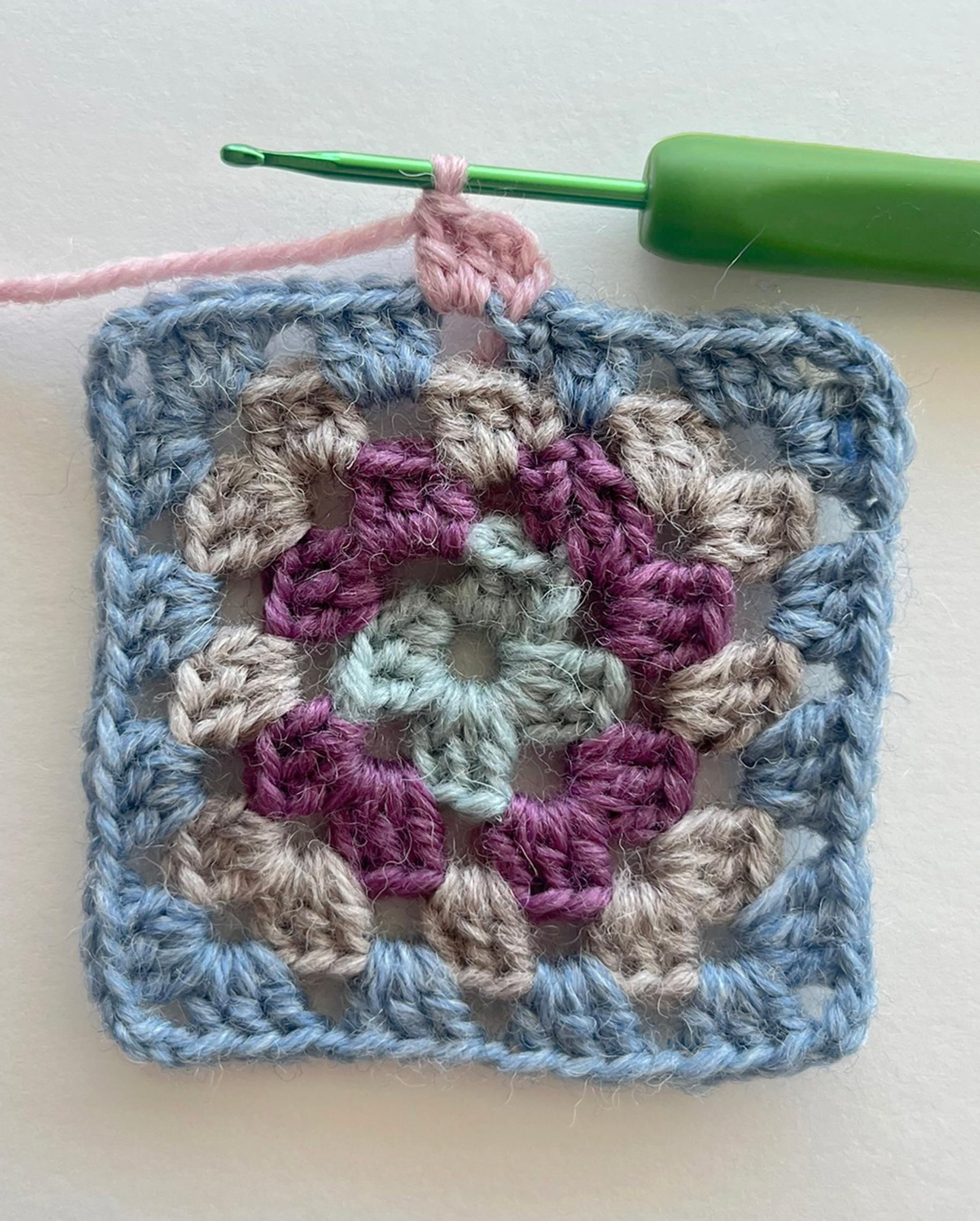 The beginning of the granny square’s fifth double-crochet round